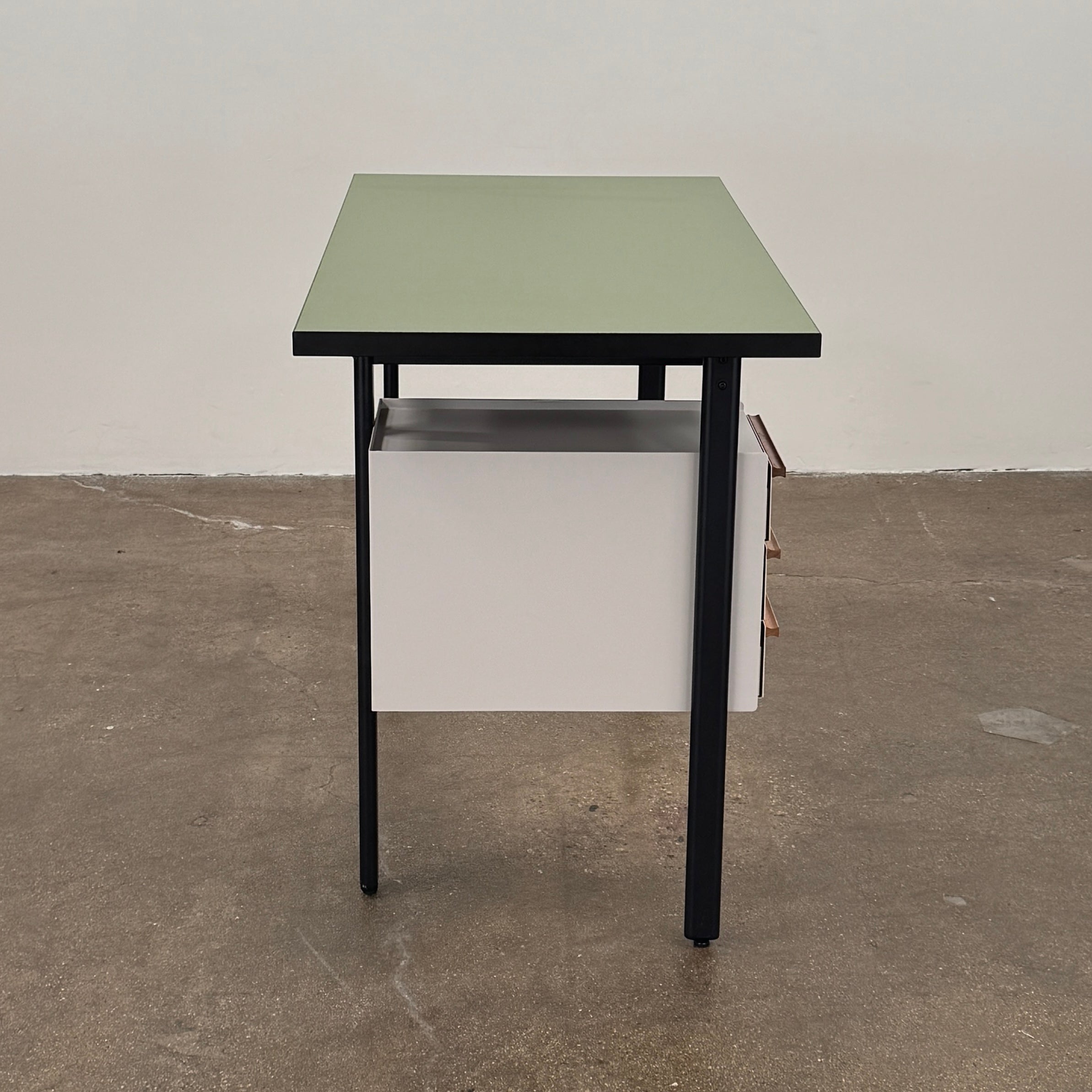 The Herman Miller Mode Desk by Herman Miller features a rectangular green tabletop, black legs, and three white drawers mounted underneath the left side—perfect as a compact desk for a minimalist workspace.
