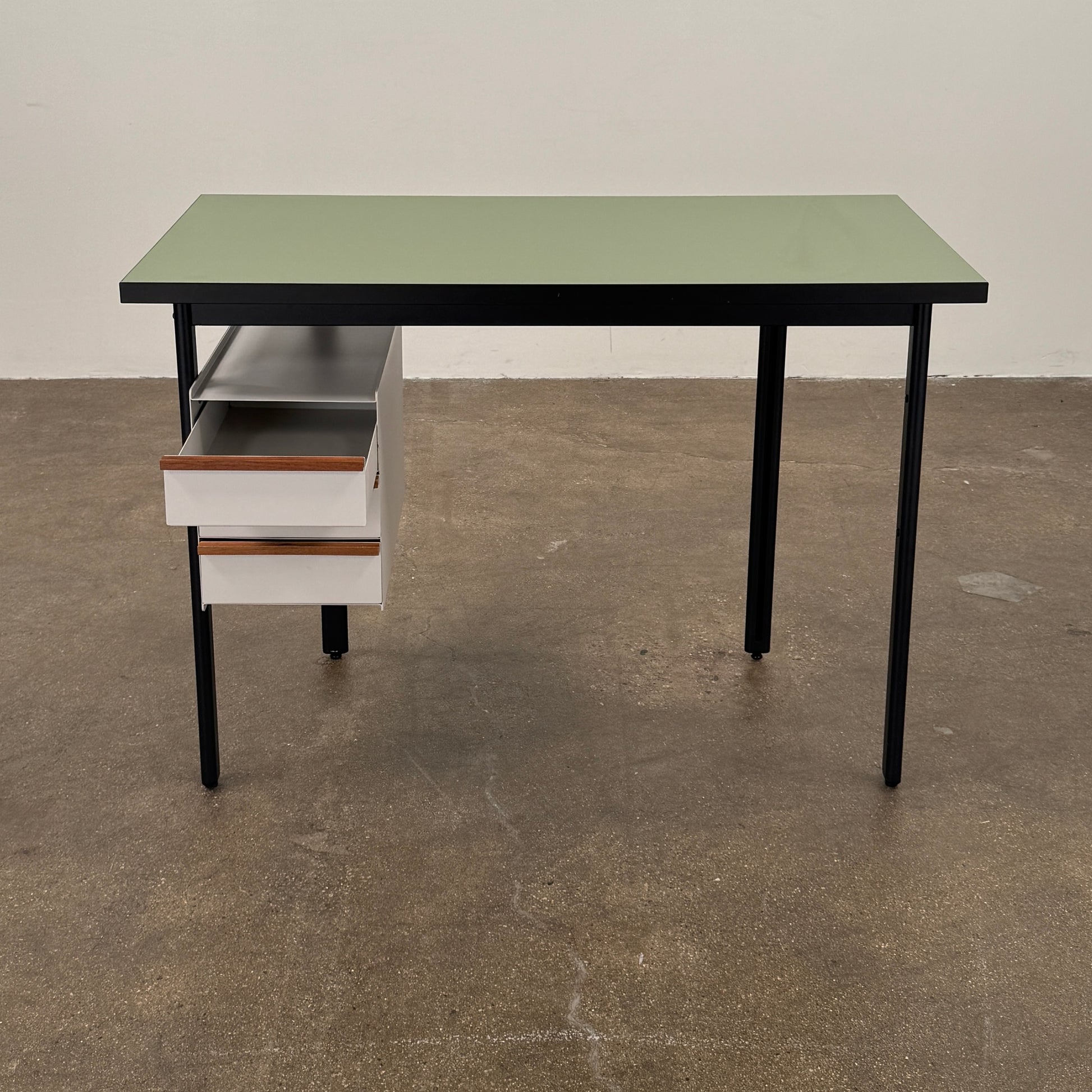 The Herman Miller Mode Desk by Herman Miller features a rectangular green tabletop, black legs, and three white drawers mounted underneath the left side—perfect as a compact desk for a minimalist workspace.