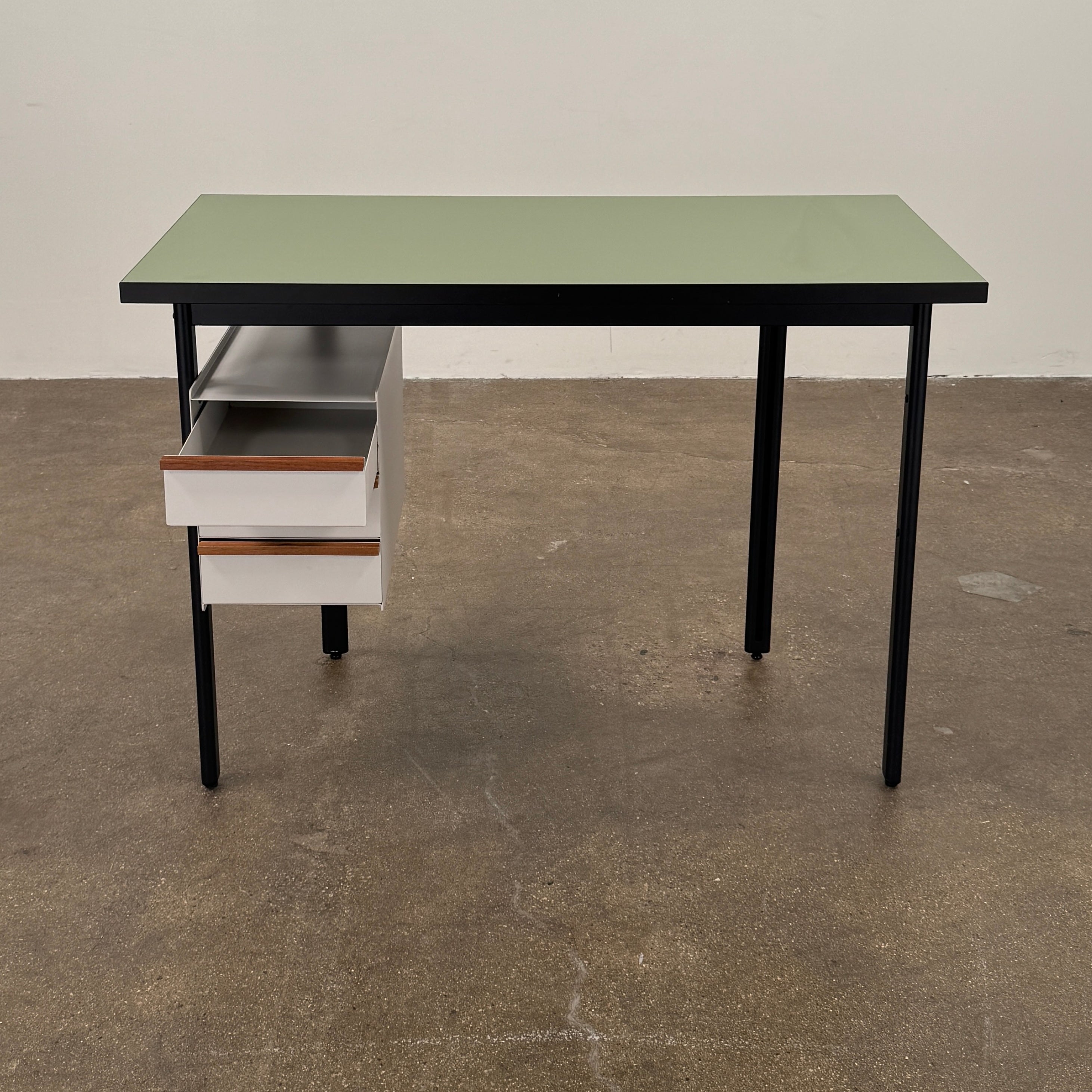 The Herman Miller Mode Desk by Herman Miller features a rectangular green tabletop, black legs, and three white drawers mounted underneath the left side—perfect as a compact desk for a minimalist workspace.