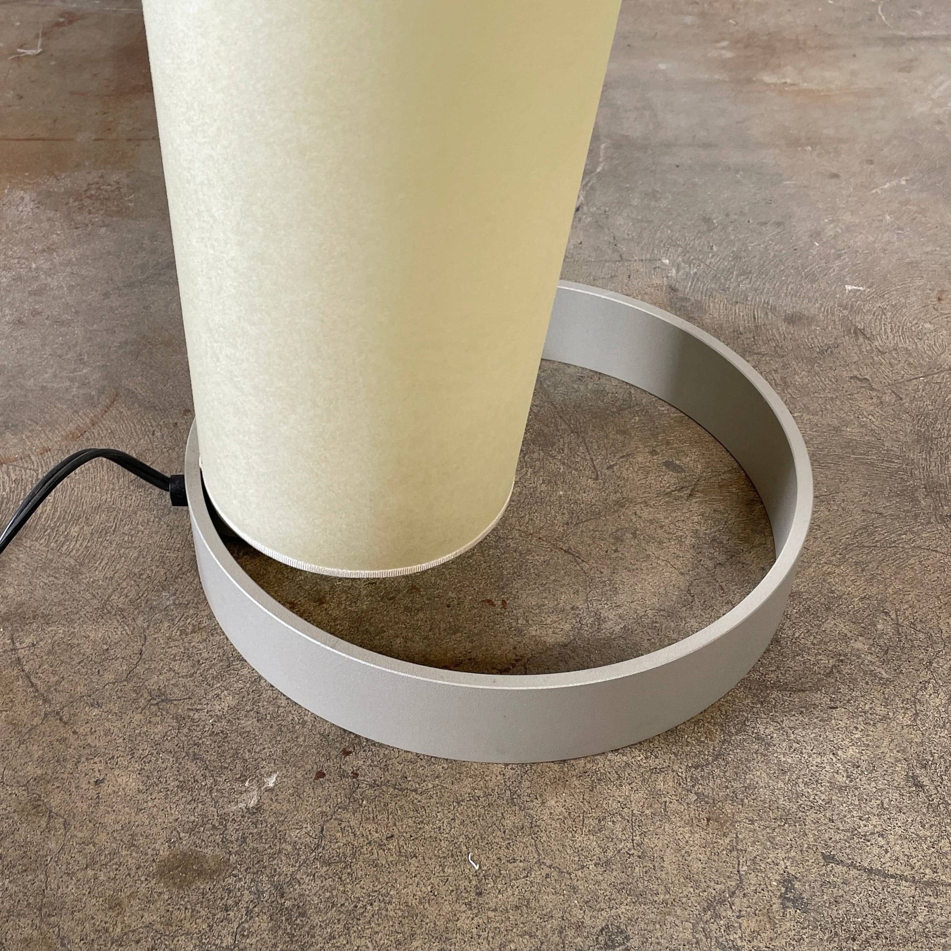A modern, cone-shaped beige Pallucco Italia Abat Jour Floor Light by Pallucco Italia features a round base and a visible power cord, blending sleek design with Italian craftsmanship.