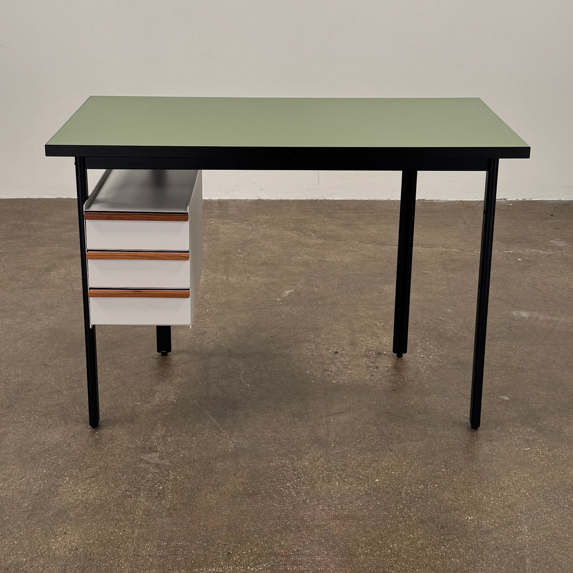 The Herman Miller Mode Desk by Herman Miller features a rectangular green tabletop, black legs, and three white drawers mounted underneath the left side—perfect as a compact desk for a minimalist workspace.