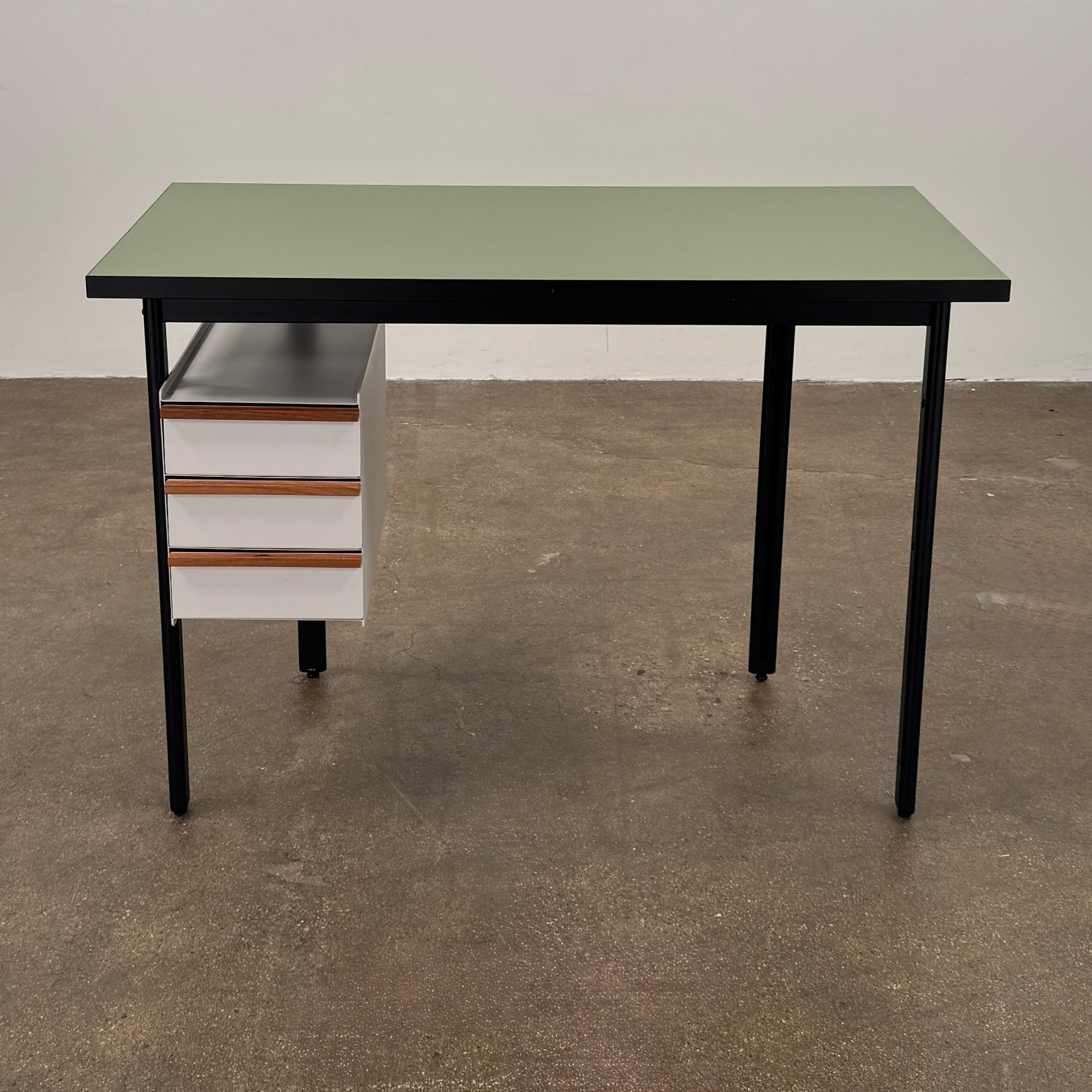The Herman Miller Mode Desk by Herman Miller features a rectangular green tabletop, black legs, and three white drawers mounted underneath the left side—perfect as a compact desk for a minimalist workspace.