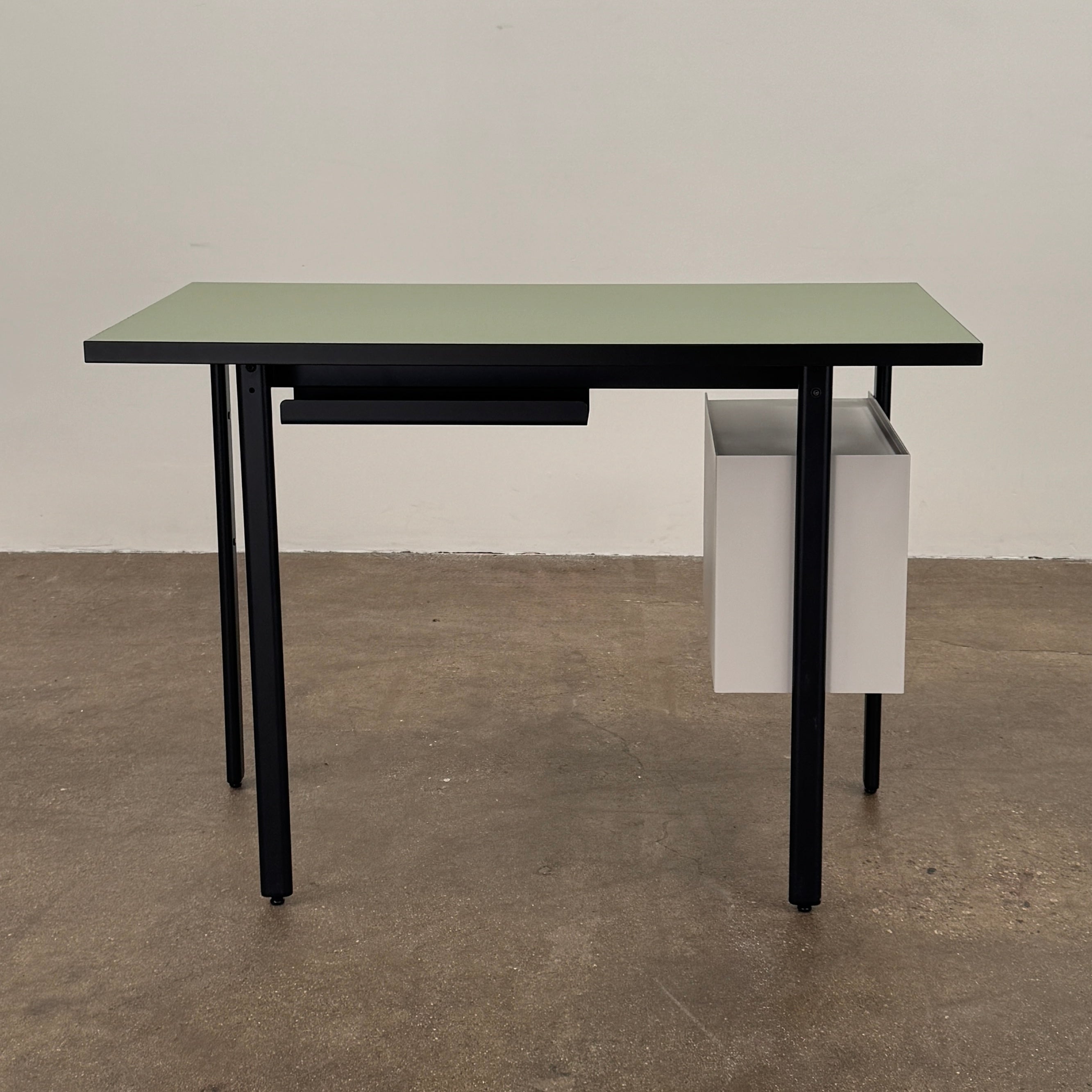 The Herman Miller Mode Desk by Herman Miller features a rectangular green tabletop, black legs, and three white drawers mounted underneath the left side—perfect as a compact desk for a minimalist workspace.