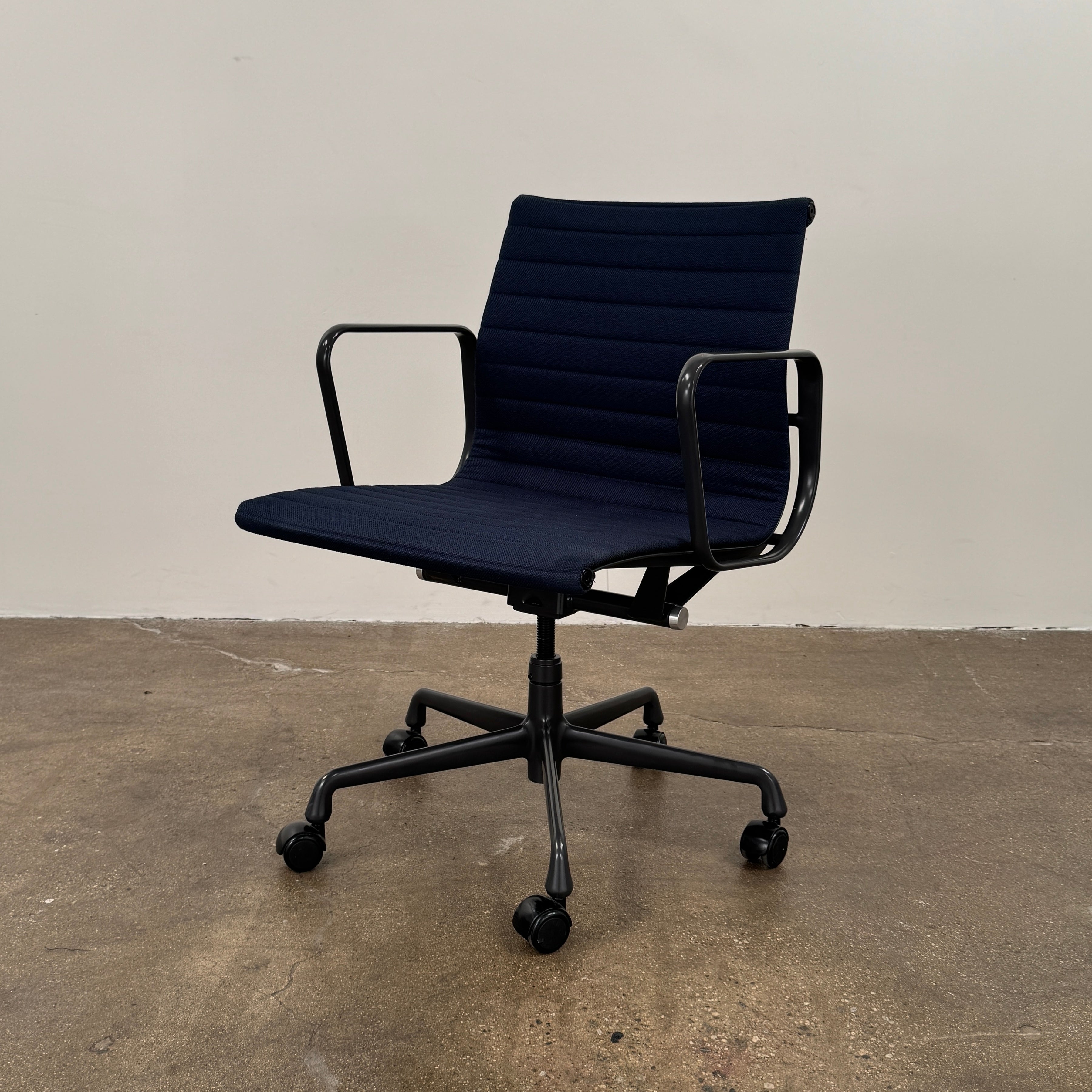 The Herman Miller Aluminum Group Office Chair in Pebble Fabric, by Herman Miller, features an ergonomic design with metal armrests and a five-wheel black base, pictured on a plain white background.