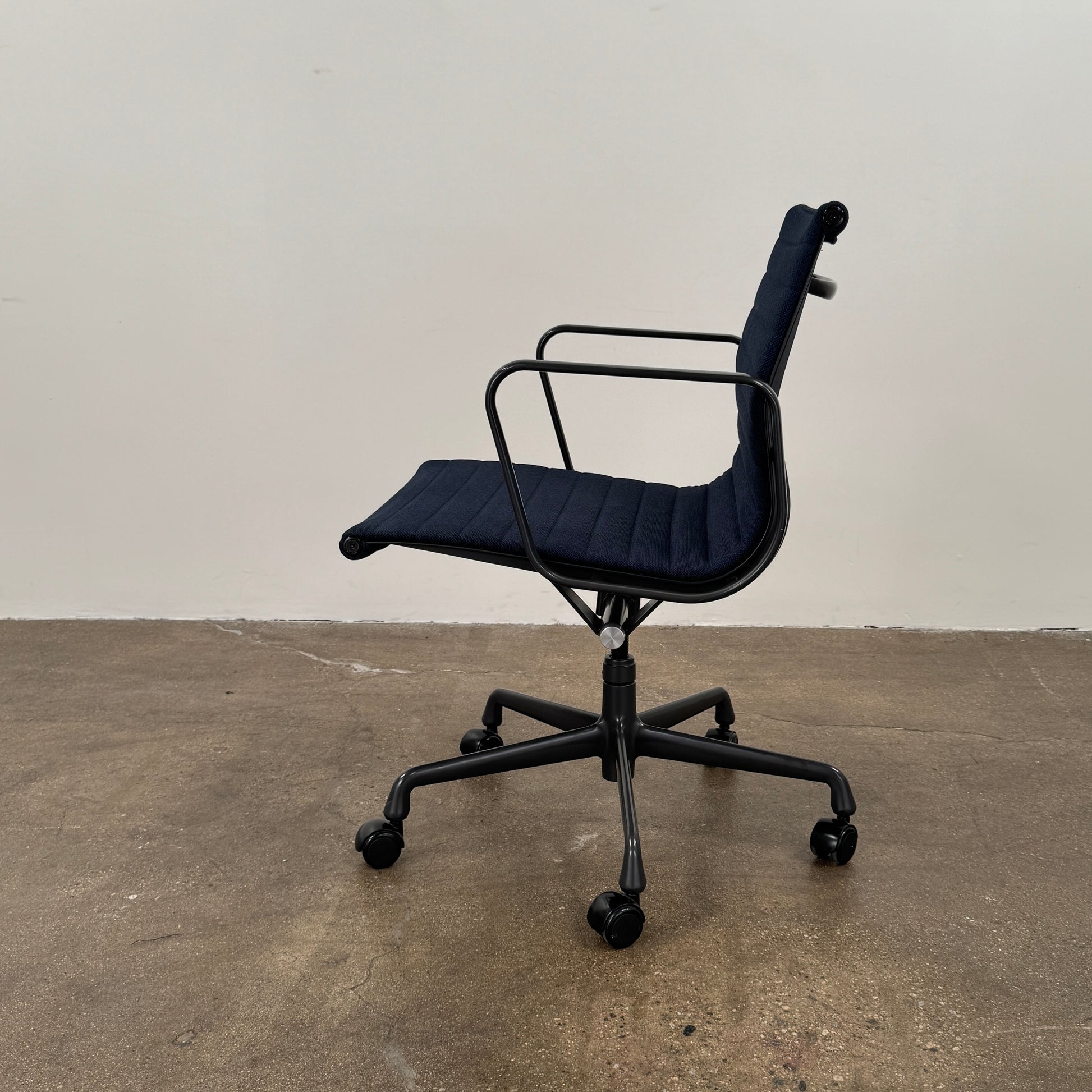 The Herman Miller Aluminum Group Office Chair in Pebble Fabric, by Herman Miller, features an ergonomic design with metal armrests and a five-wheel black base, pictured on a plain white background.