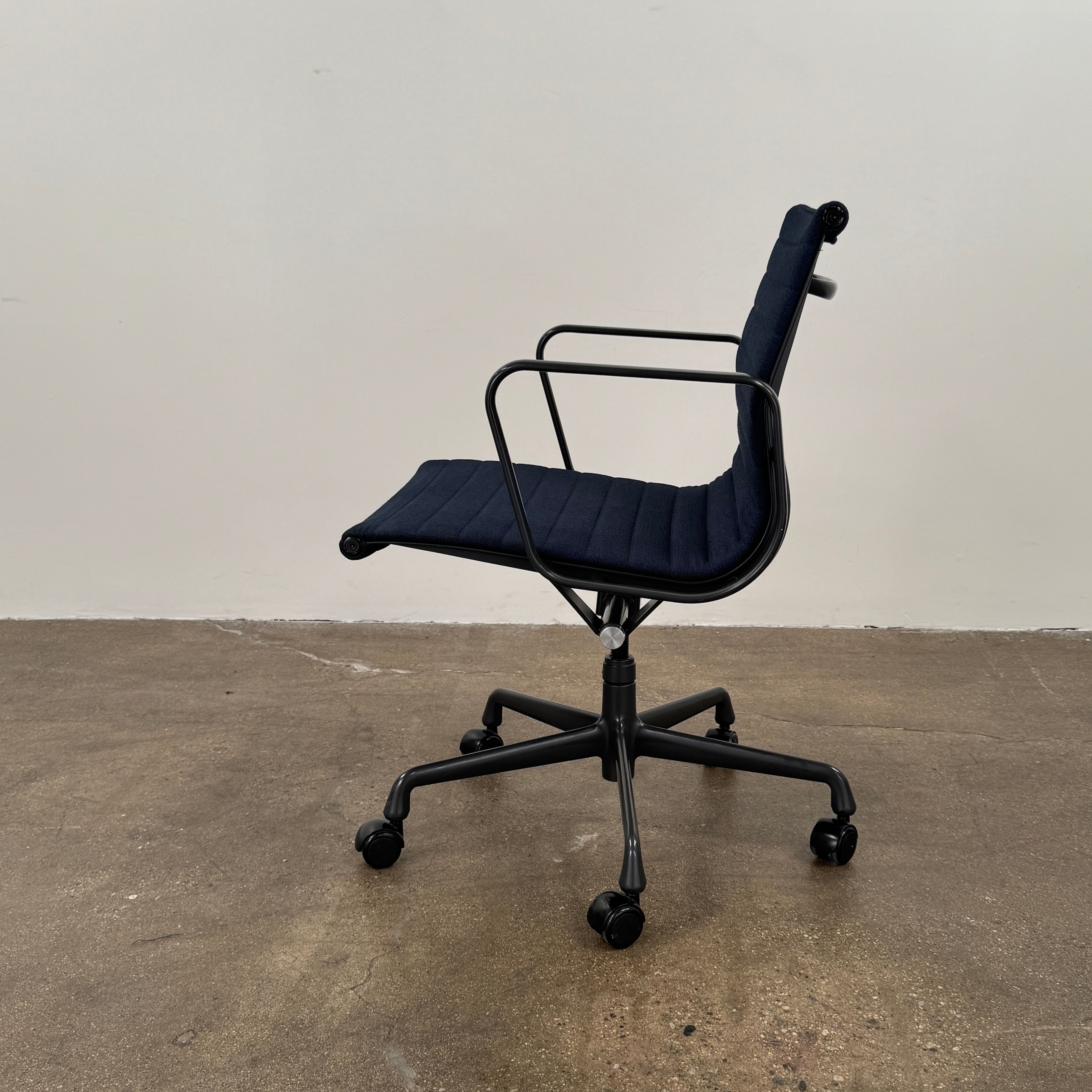 The Herman Miller Aluminum Group Office Chair in Pebble Fabric, by Herman Miller, features an ergonomic design with metal armrests and a five-wheel black base, pictured on a plain white background.