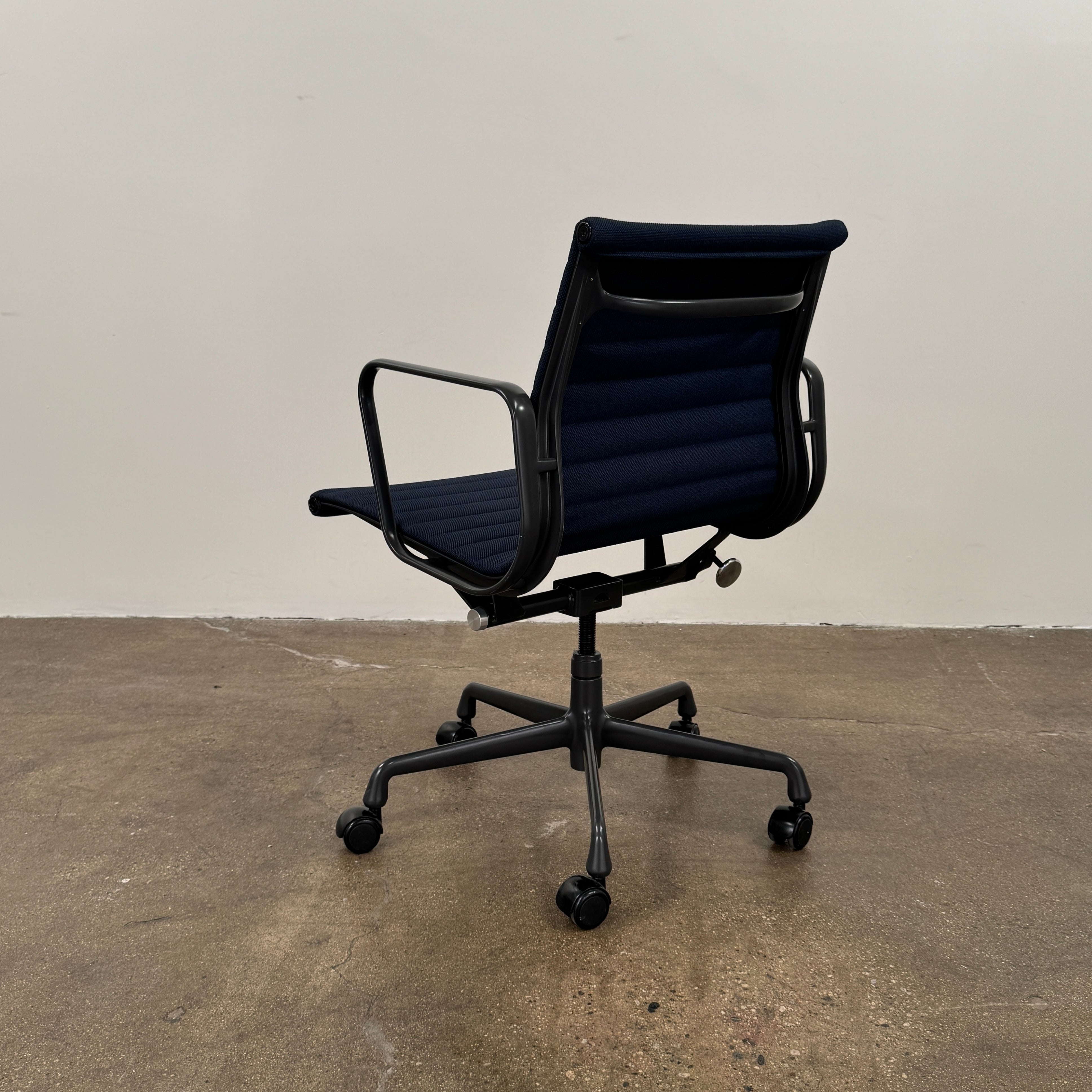 The Herman Miller Aluminum Group Office Chair in Pebble Fabric, by Herman Miller, features an ergonomic design with metal armrests and a five-wheel black base, pictured on a plain white background.