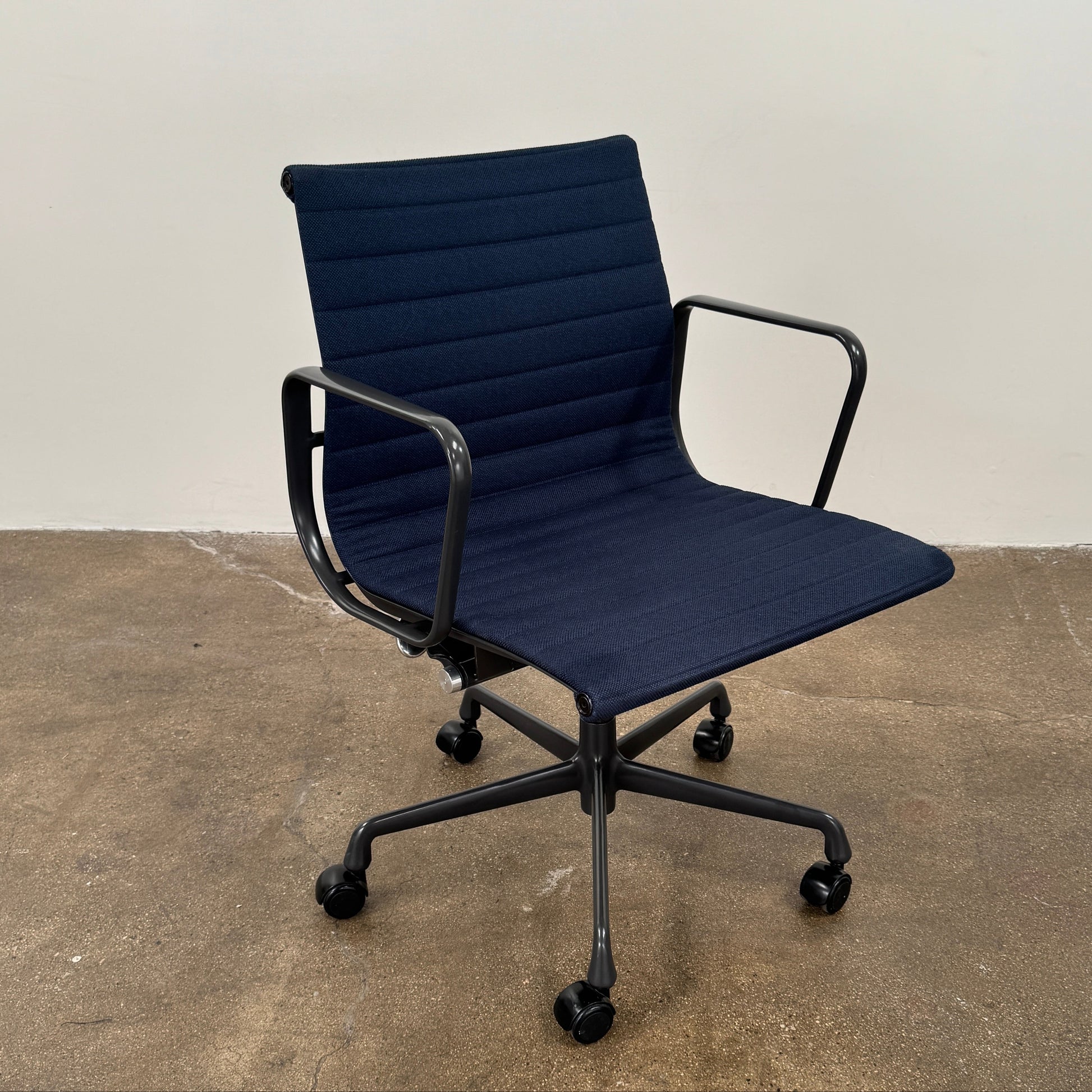 The Herman Miller Aluminum Group Office Chair in Pebble Fabric, by Herman Miller, features an ergonomic design with metal armrests and a five-wheel black base, pictured on a plain white background.