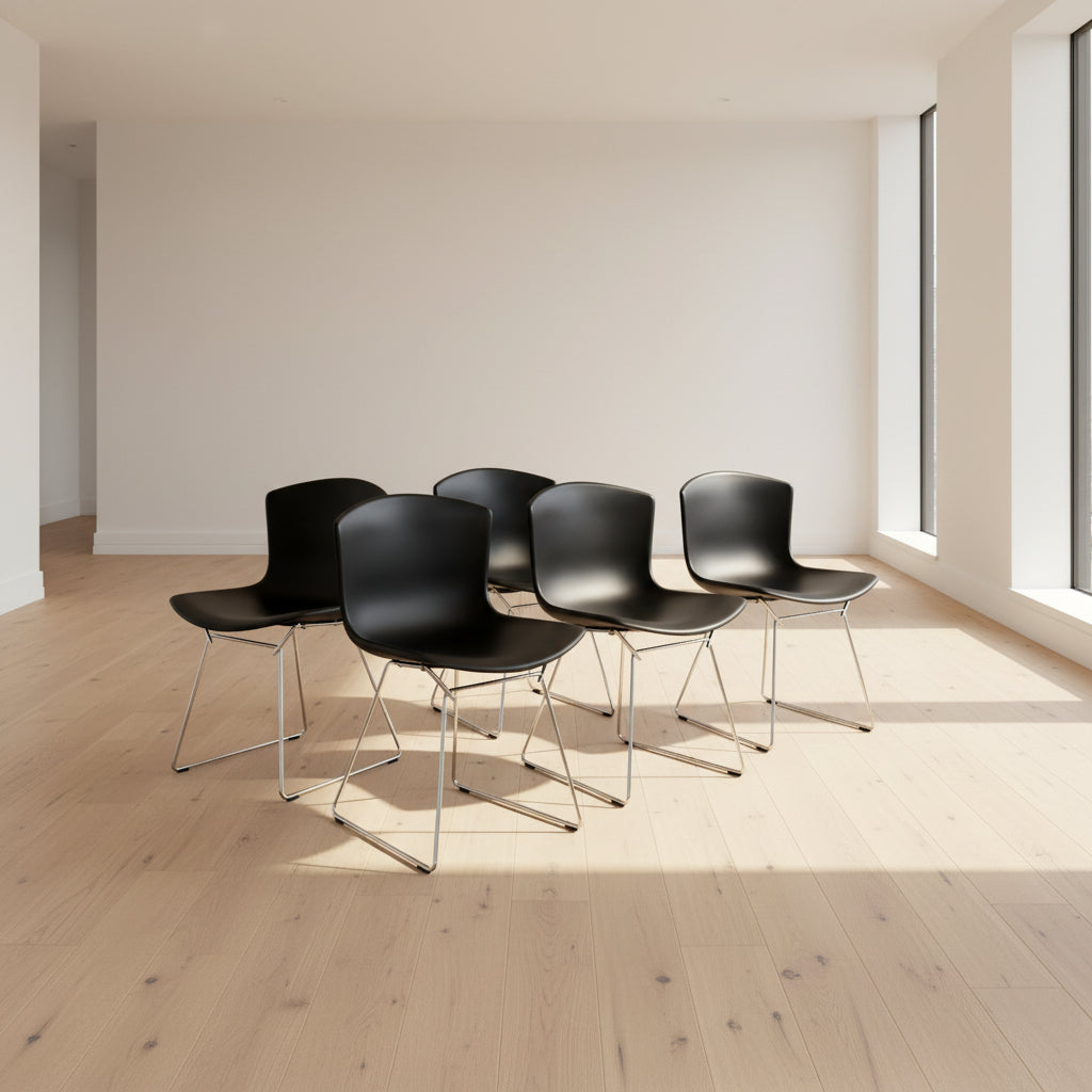 Eight Knoll Bertoia Molded Shell Chairs by Knoll, featuring black plastic seats and metal legs, are arranged in two rows on a white background, showcasing the sleek, timeless silhouette inspired by mid-century design.