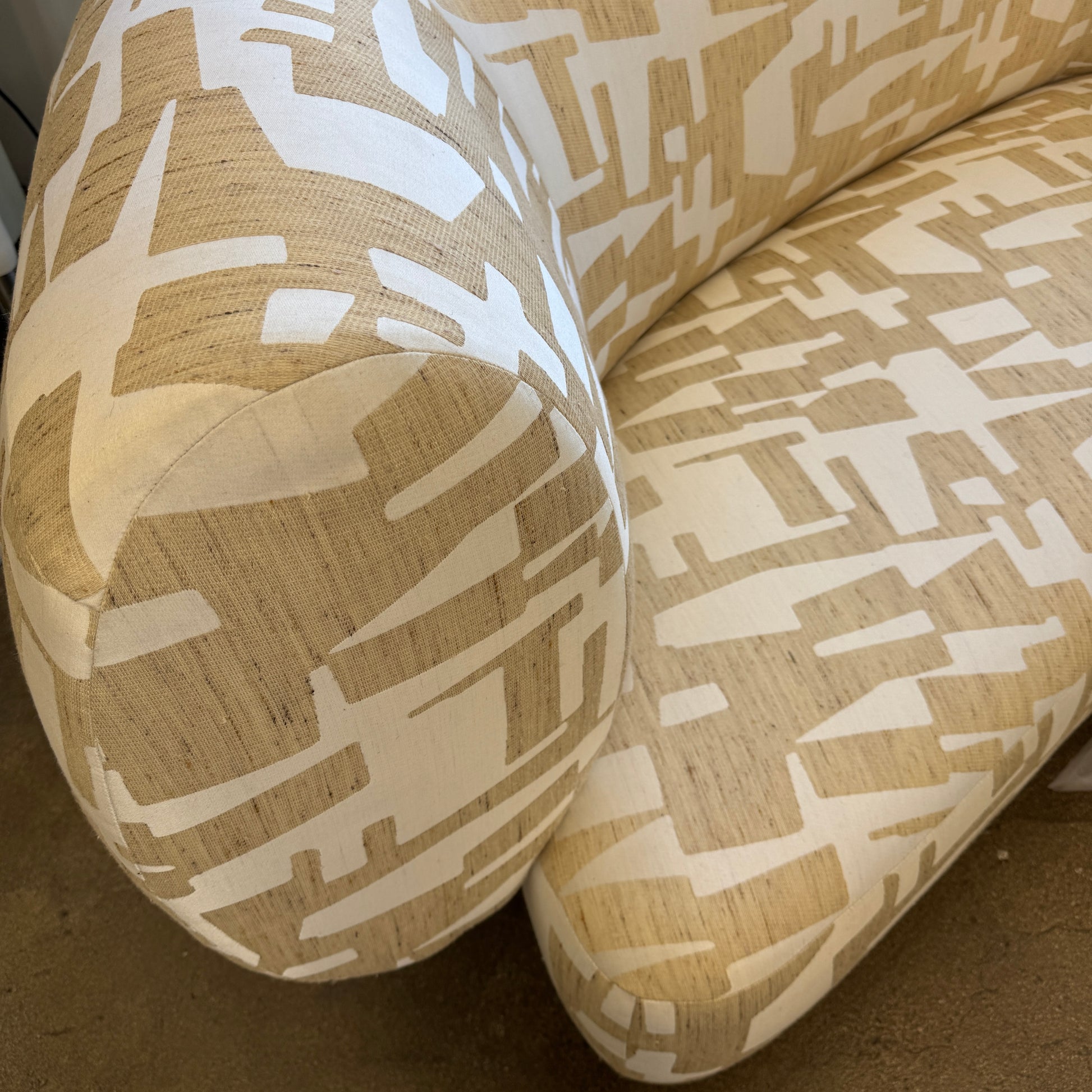 The Muskoka Living Custom Sofa by Muskoka Living showcases an asymmetrical contemporary silhouette with a low backrest, upholstered in luxurious Italian jacquard fabric featuring an abstract geometric pattern in beige, and is presented against a plain white background.