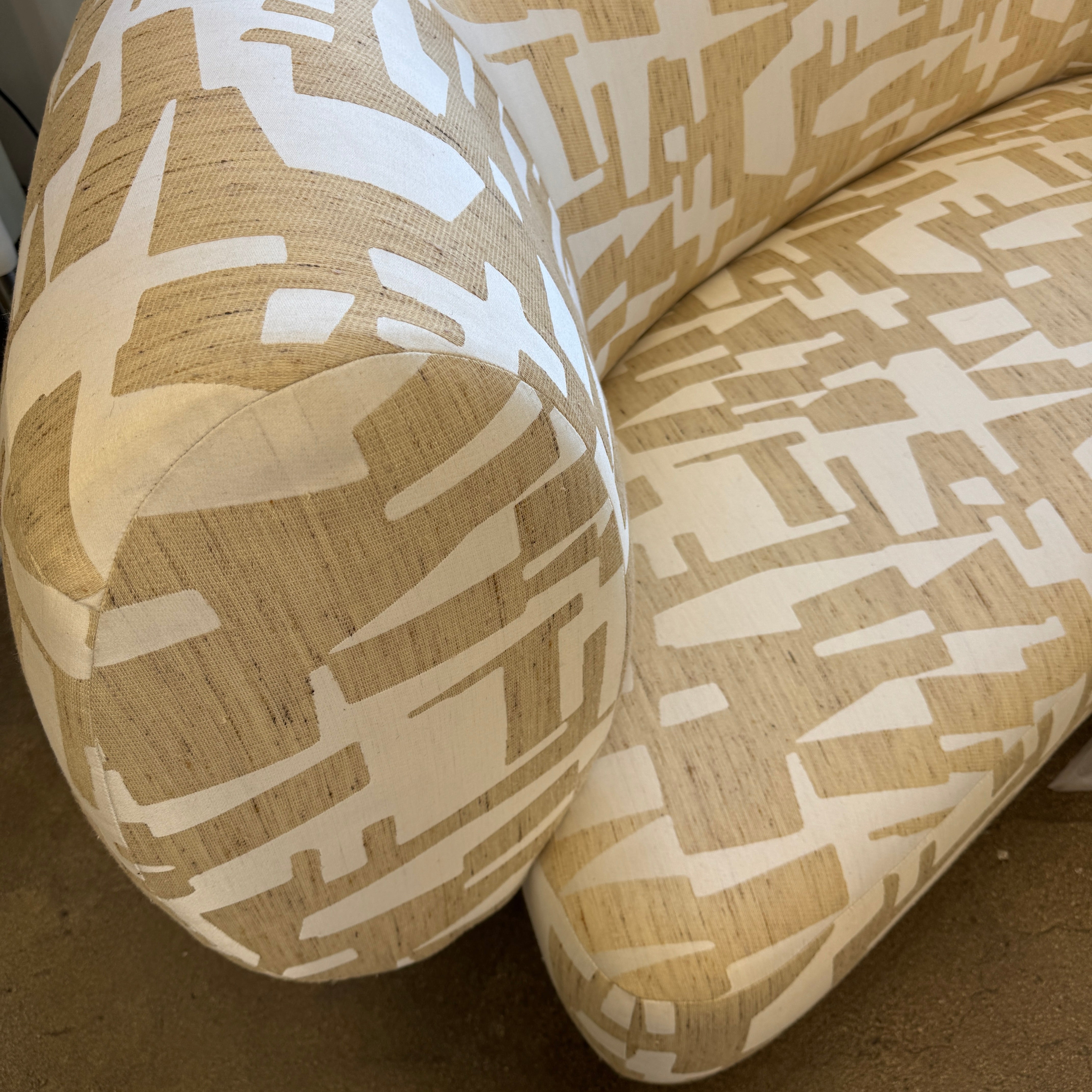 The Muskoka Living Custom Sofa by Muskoka Living showcases an asymmetrical contemporary silhouette with a low backrest, upholstered in luxurious Italian jacquard fabric featuring an abstract geometric pattern in beige, and is presented against a plain white background.