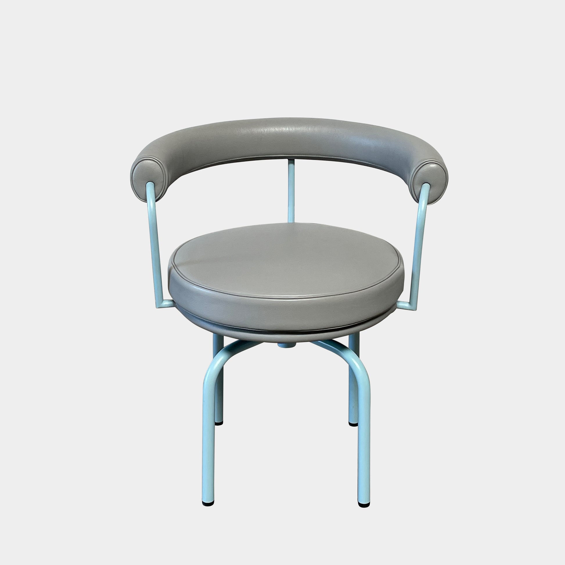 A gray leather Cassina LC7 Swivel Chair, featuring a circular seat, tubular backrest, and light blue metal legs, embodies modern design by Le Corbusier on a white background.