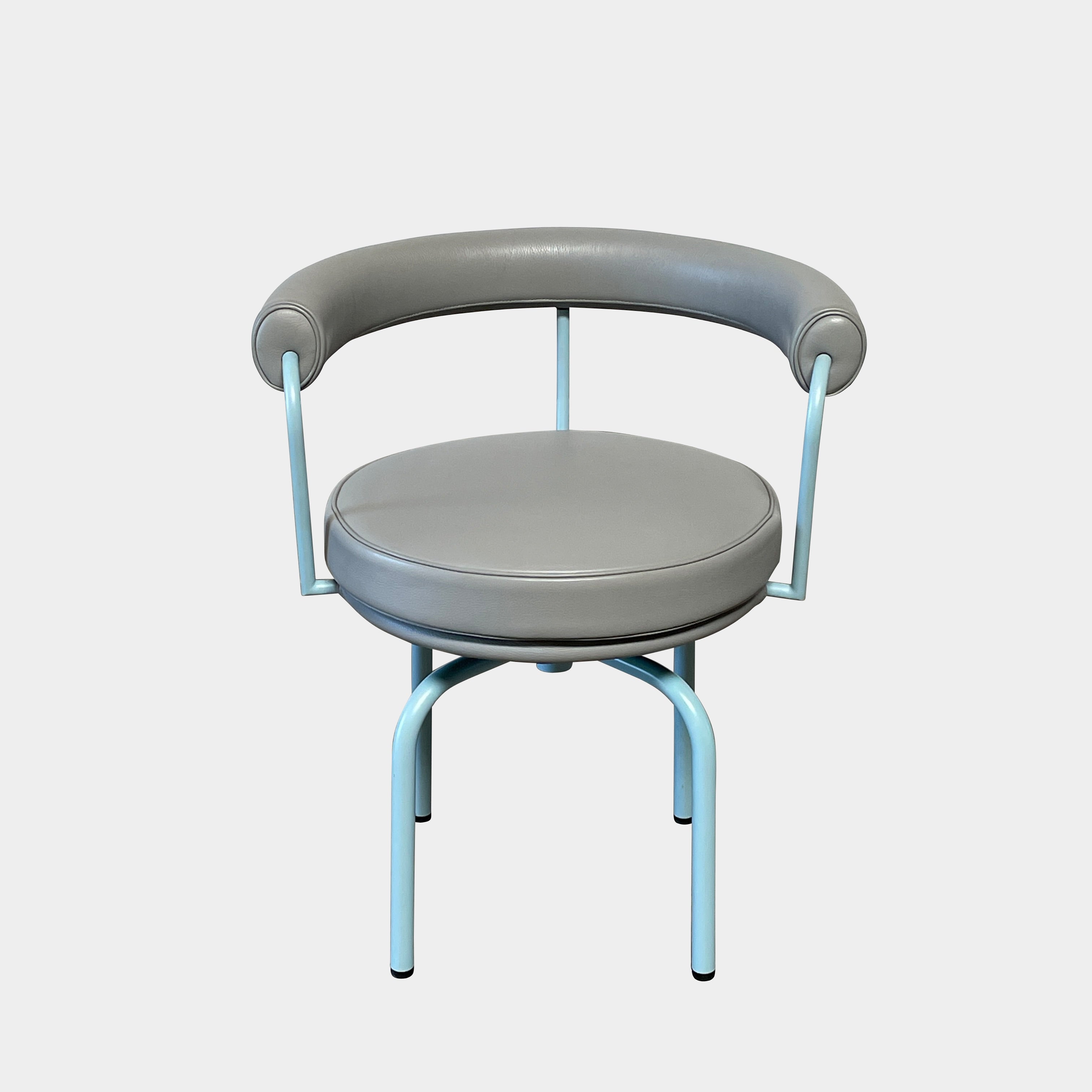 A gray leather Cassina LC7 Swivel Chair, featuring a circular seat, tubular backrest, and light blue metal legs, embodies modern design by Le Corbusier on a white background.
