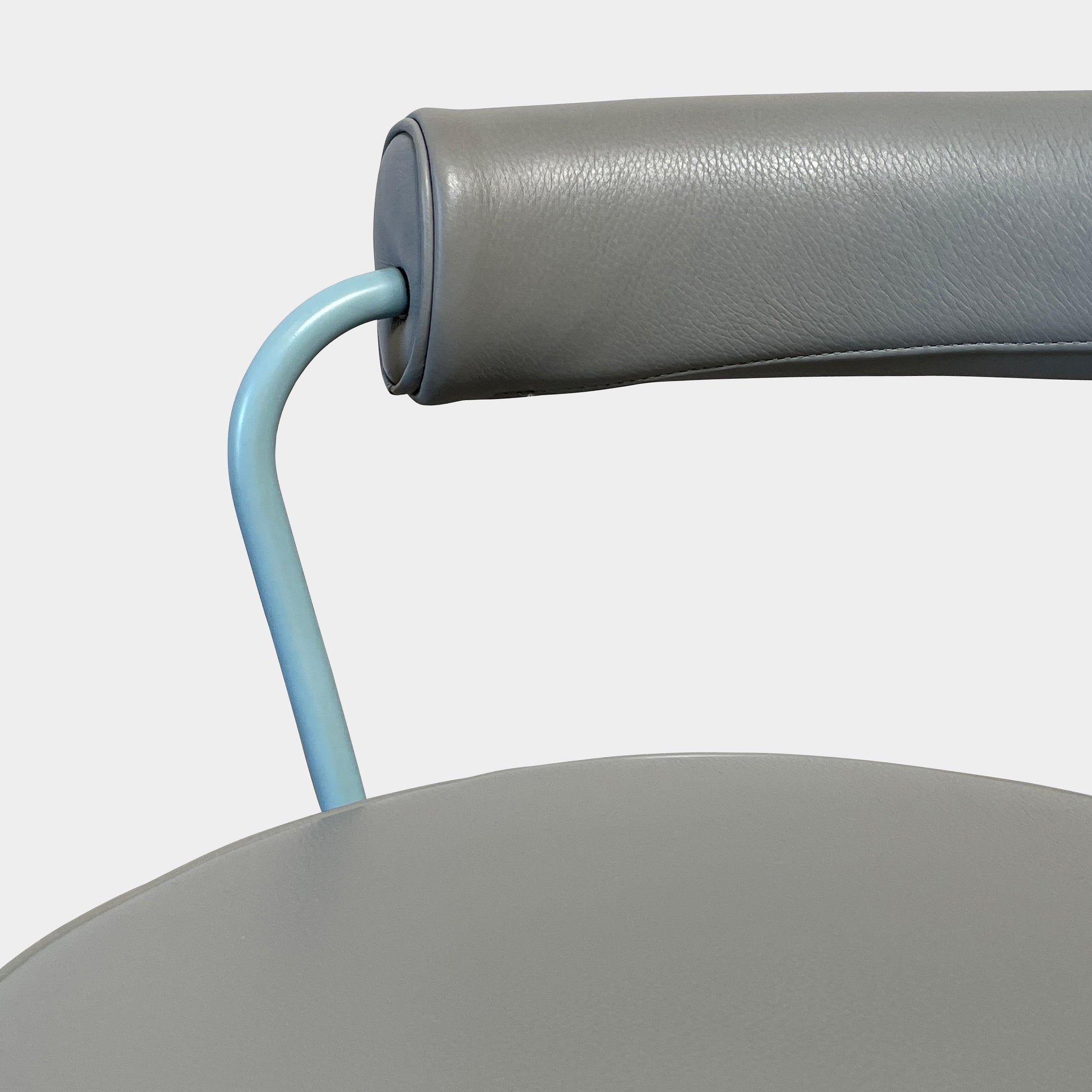 A gray leather Cassina LC7 Swivel Chair, featuring a circular seat, tubular backrest, and light blue metal legs, embodies modern design by Le Corbusier on a white background.