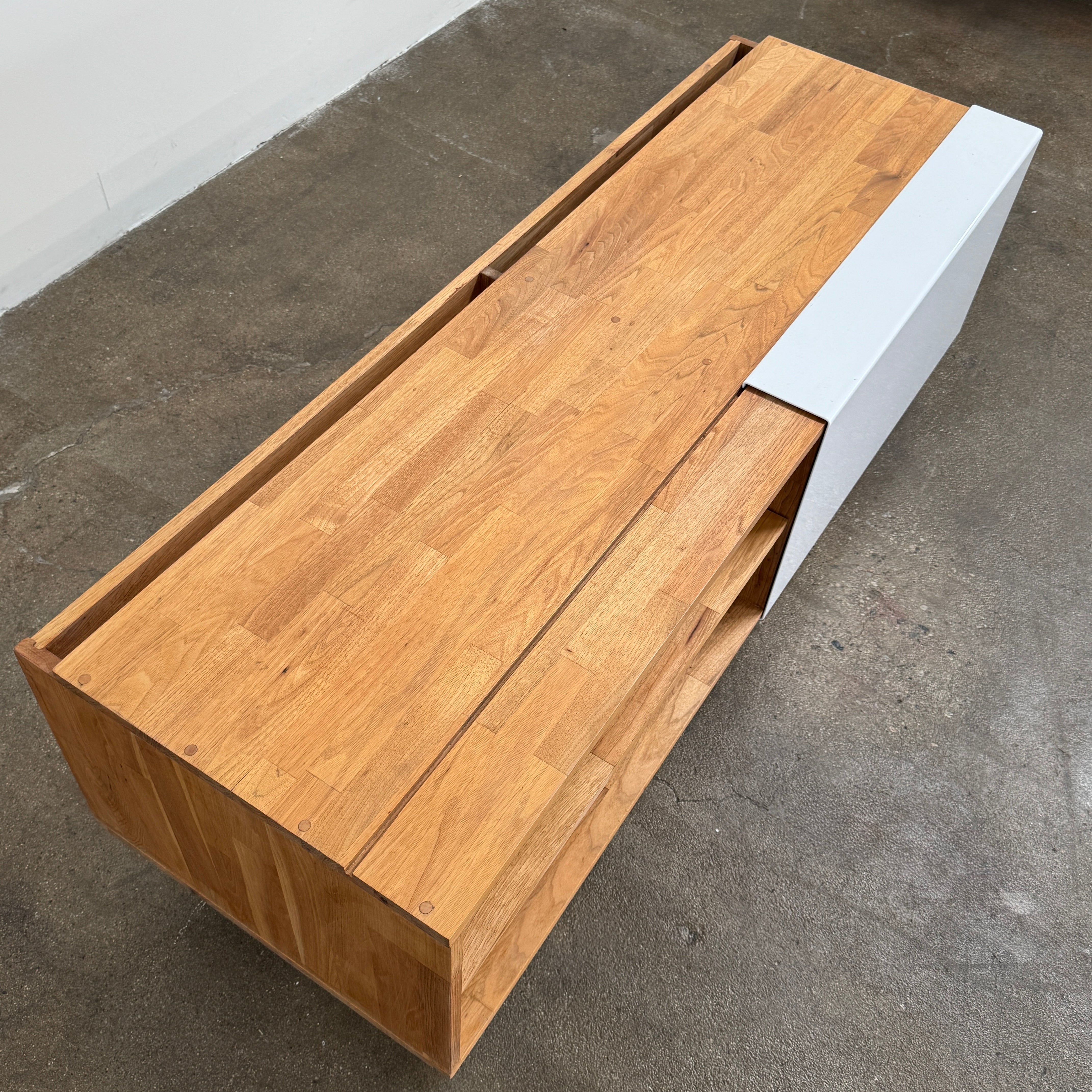The Mash Studios LAXseries Media Console by Mash Studios is a modern wooden TV stand crafted from solid English walnut, featuring a sleek white sliding door, two open shelves with wire management for convenience, and distinctive angled legs, shown against a plain white background.