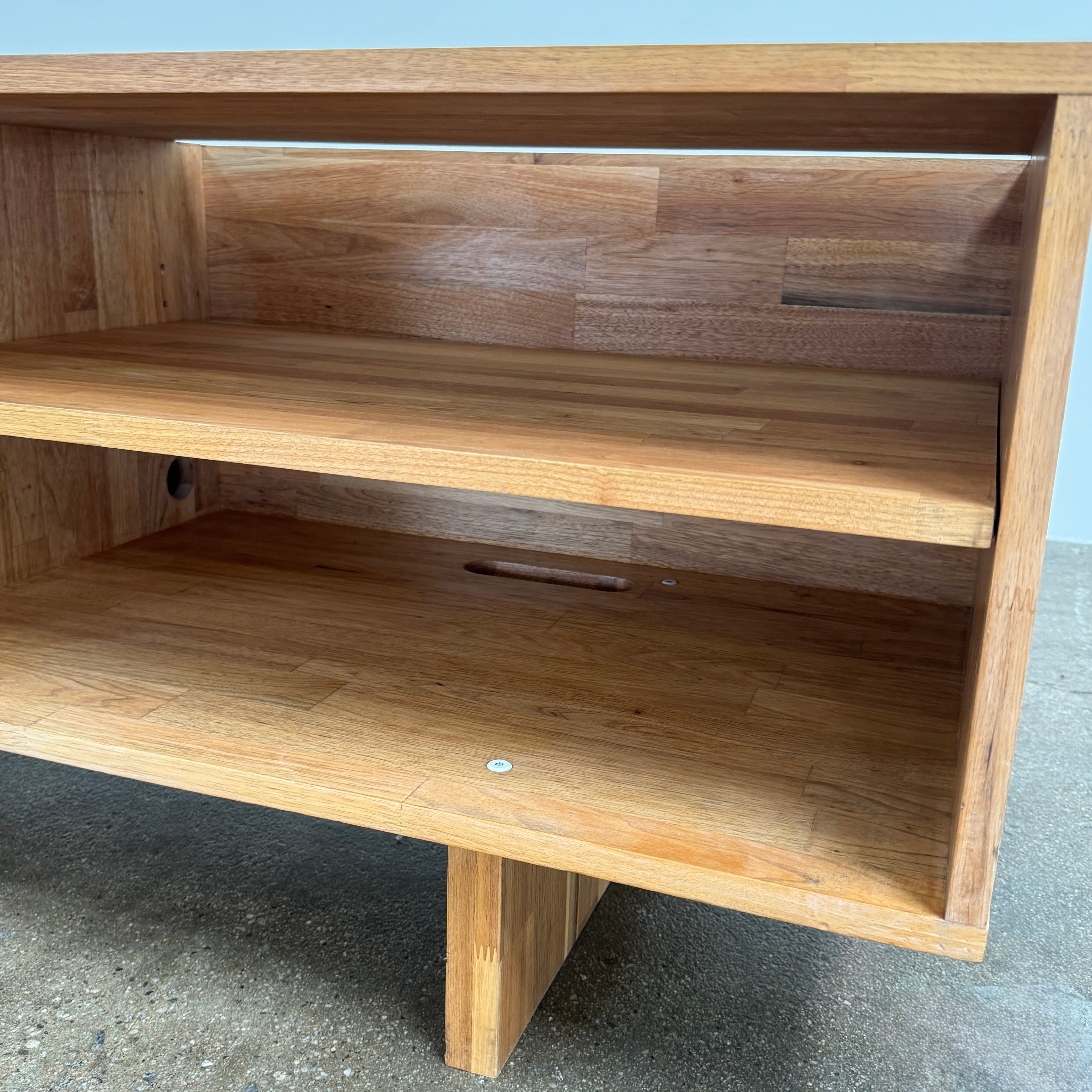 The Mash Studios LAXseries Media Console by Mash Studios is a modern wooden TV stand crafted from solid English walnut, featuring a sleek white sliding door, two open shelves with wire management for convenience, and distinctive angled legs, shown against a plain white background.