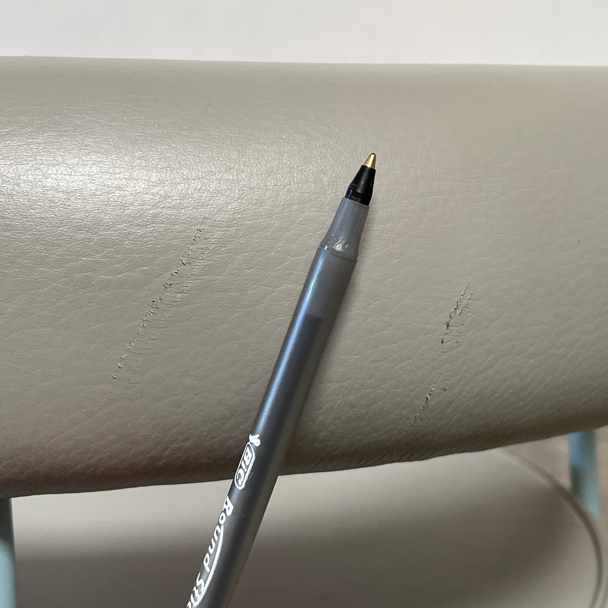 A gray leather Cassina LC7 Swivel Chair, featuring a circular seat, tubular backrest, and light blue metal legs, embodies modern design by Le Corbusier on a white background.