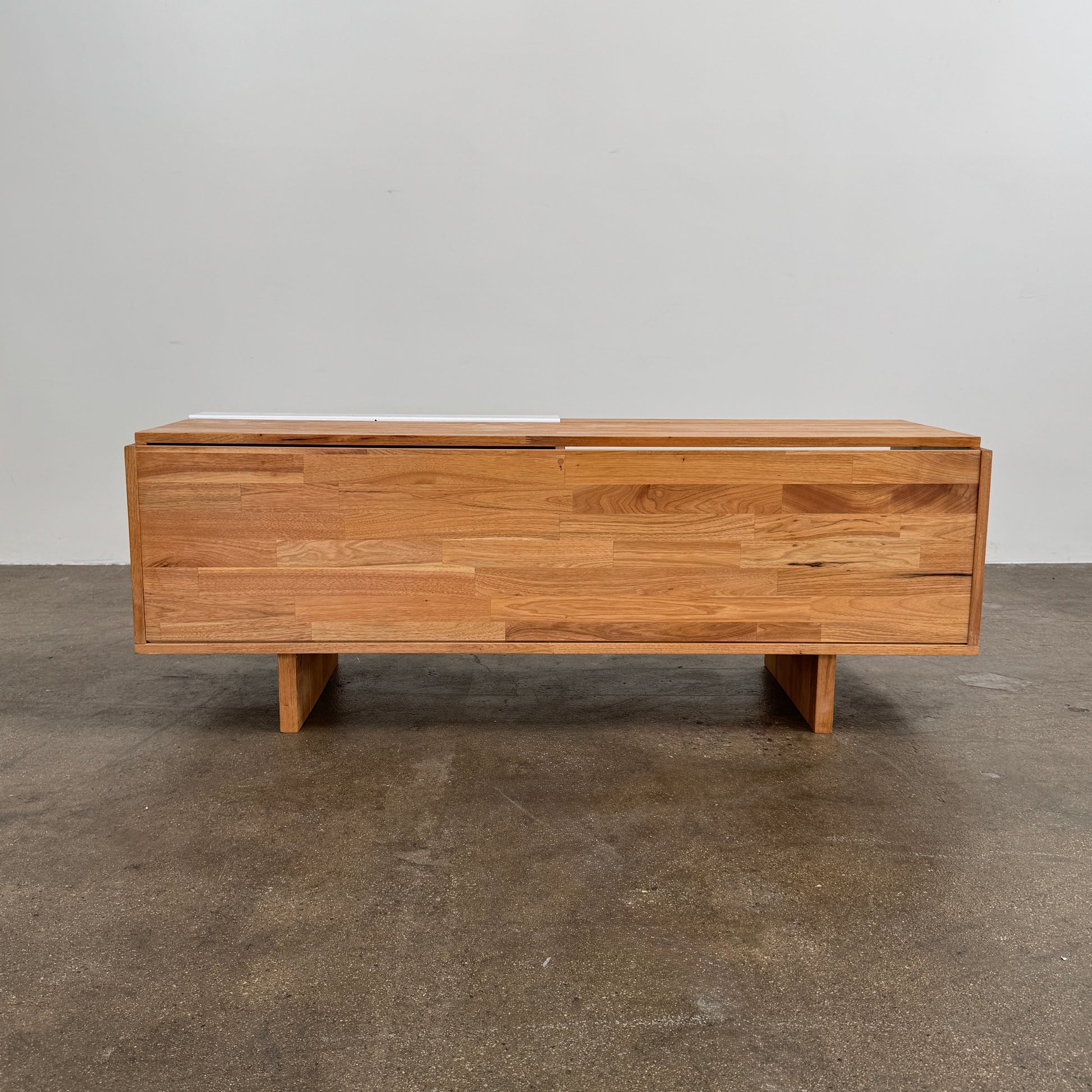 The Mash Studios LAXseries Media Console by Mash Studios is a modern wooden TV stand crafted from solid English walnut, featuring a sleek white sliding door, two open shelves with wire management for convenience, and distinctive angled legs, shown against a plain white background.