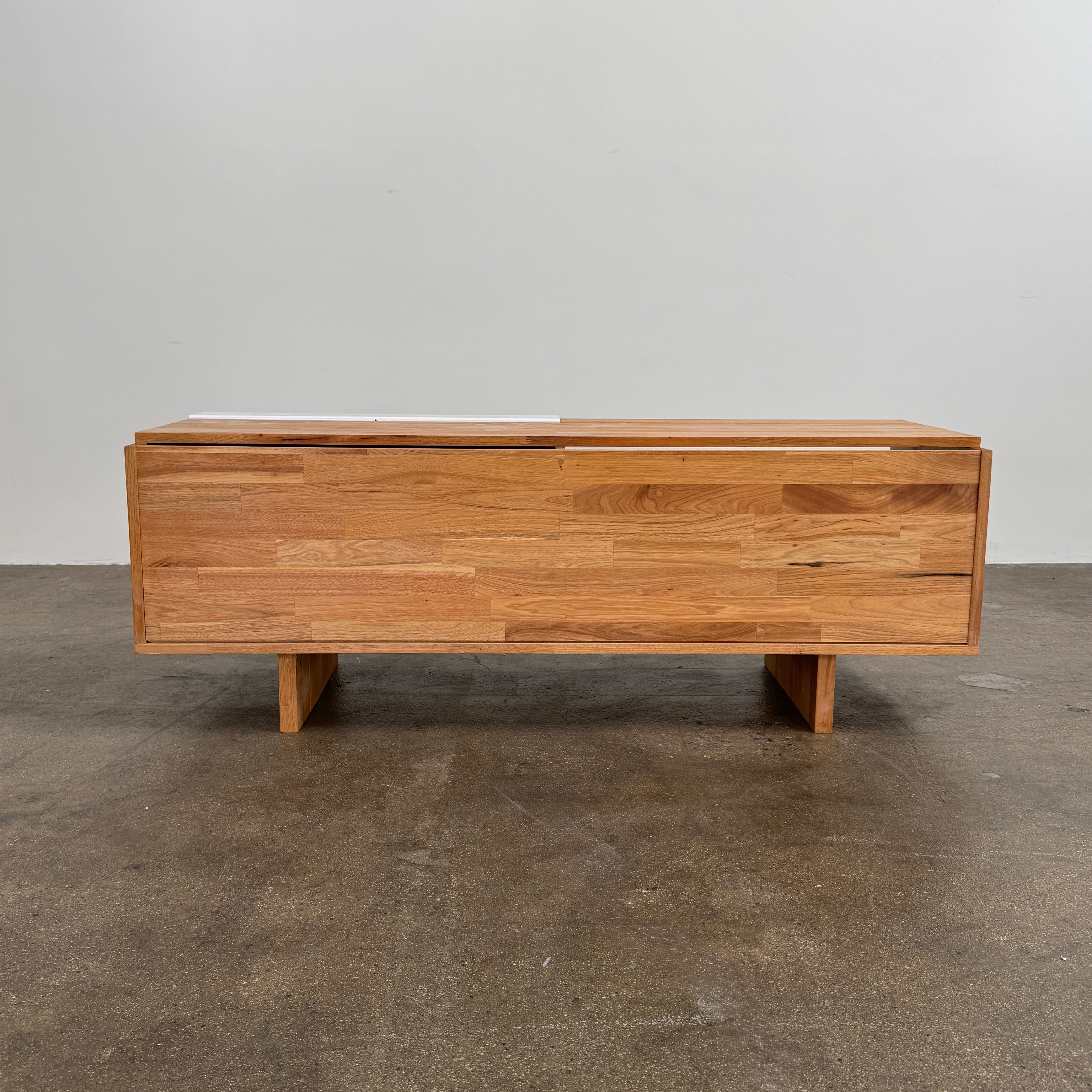The Mash Studios LAXseries Media Console by Mash Studios is a modern wooden TV stand crafted from solid English walnut, featuring a sleek white sliding door, two open shelves with wire management for convenience, and distinctive angled legs, shown against a plain white background.