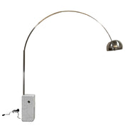 The DWR Arco Floor Lamp by DWR features a marble base, a sleek metal arching stem, and a dome-shaped metal shade; inspired by Italian craftsmanship and Achille Castiglioni’s legendary design, with an electrical cord and plug visible near the base.