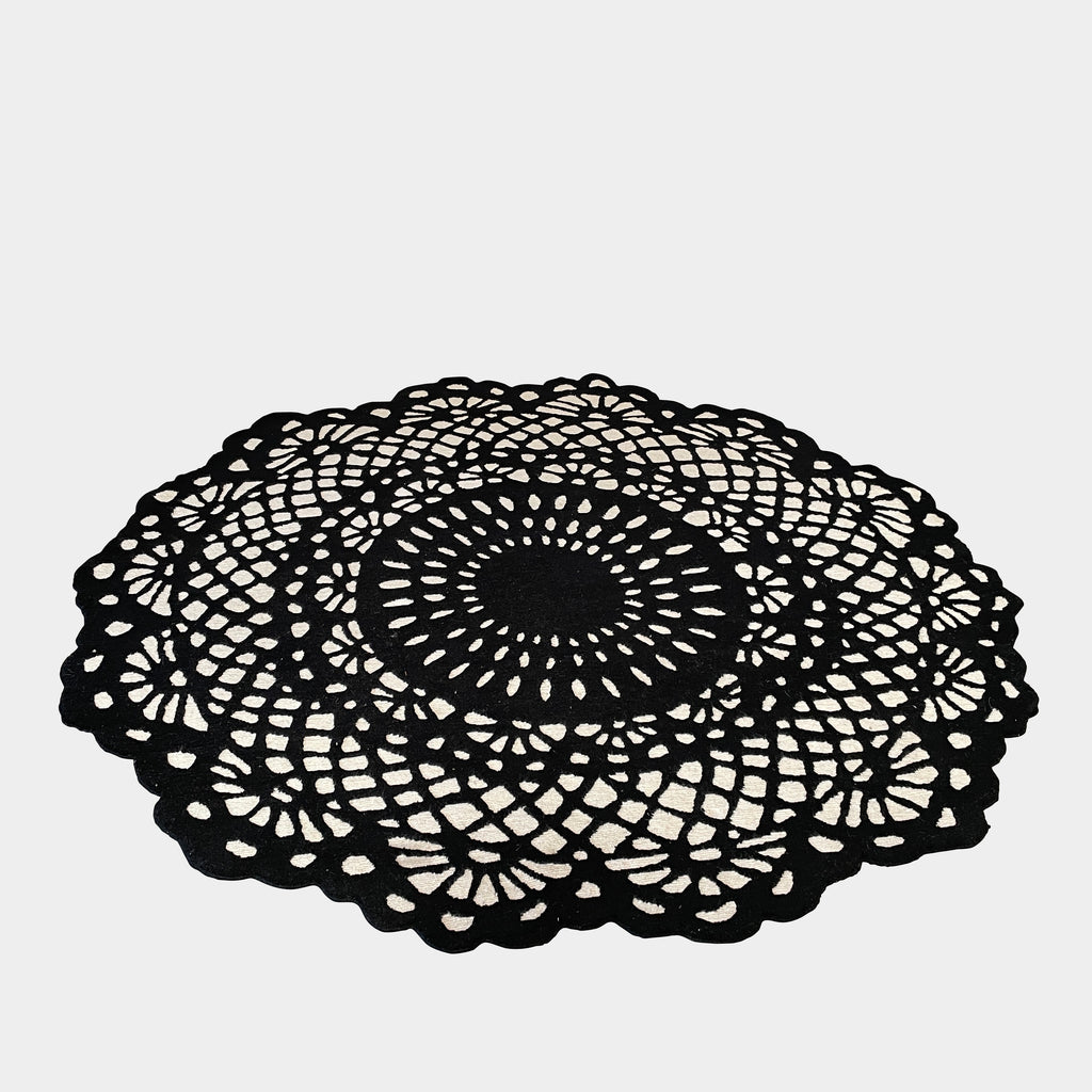A Delinear Doily 6' Round Black and Cream Rug made of Himalayan wool, delicately delinear, placed on a white surface.