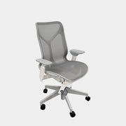 A sleek, modern white Herman Miller Cosm Office Chair featuring a mesh back and seat, supportive armrests, and five caster wheels is showcased on a concrete floor against an off-white wall. Designed by Herman Miller, this ergonomic chair seamlessly combines contemporary style with exceptional comfort.