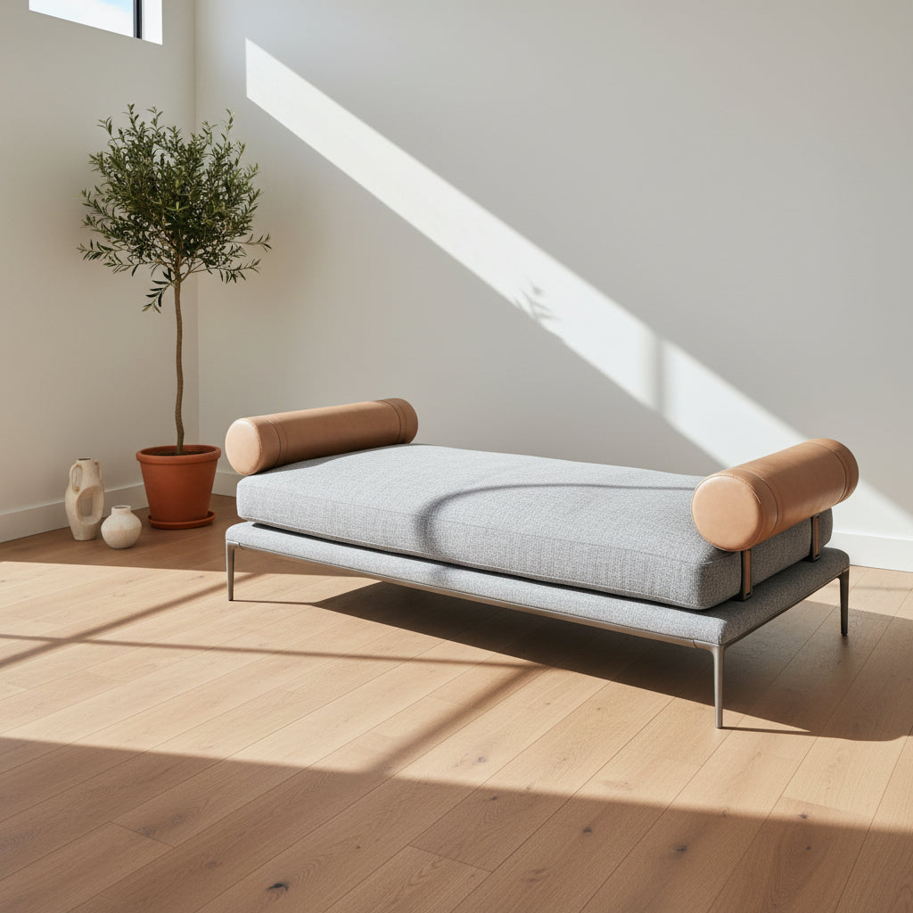 The B&B Italia Atoll Bench with Leather Bolsters by B&B Italia is a modern gray upholstered daybed featuring two cylindrical tan leather bolsters at each end, set on a sleek black metal frame and shown against a white background.