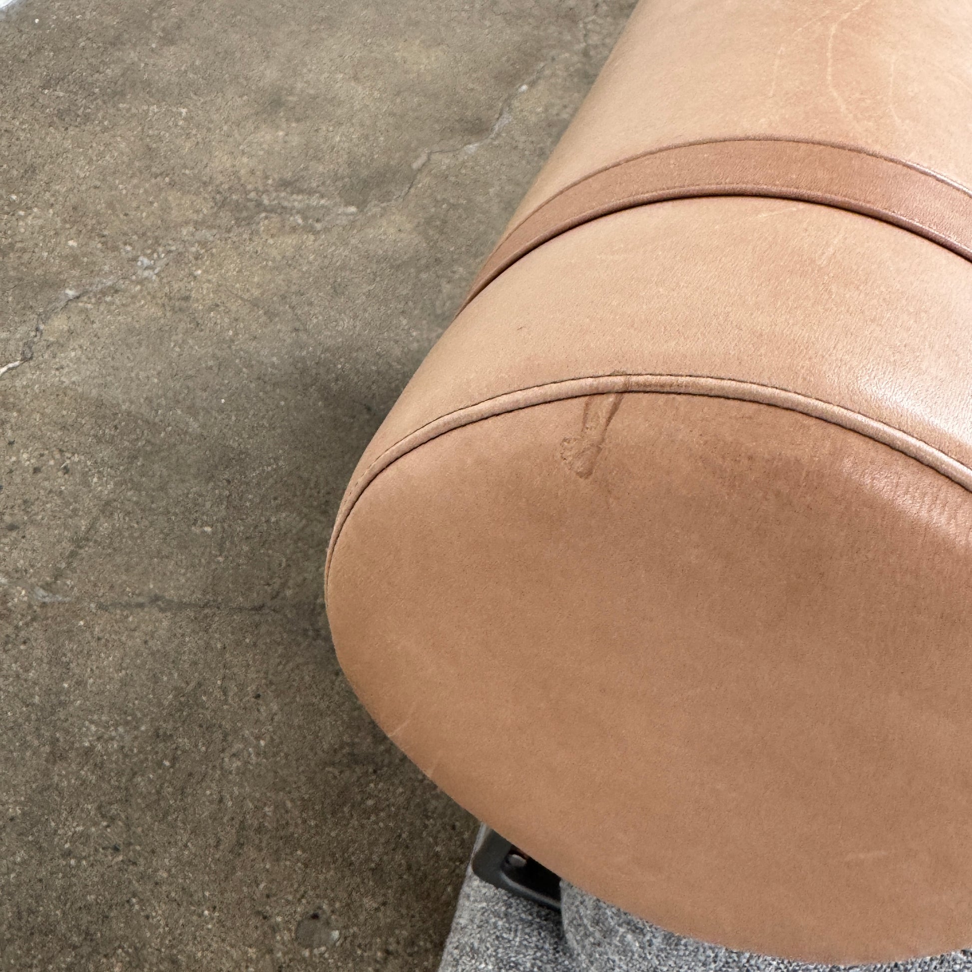 The B&B Italia Atoll Bench with Leather Bolsters by B&B Italia is a modern gray upholstered daybed featuring two cylindrical tan leather bolsters at each end, set on a sleek black metal frame and shown against a white background.