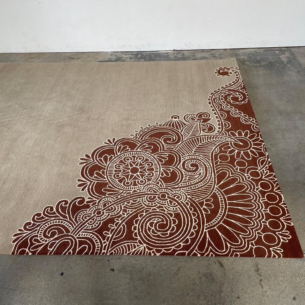 A Delinear Henna Taupe Wool 8'X10' Rug with a red and beige paisley design.