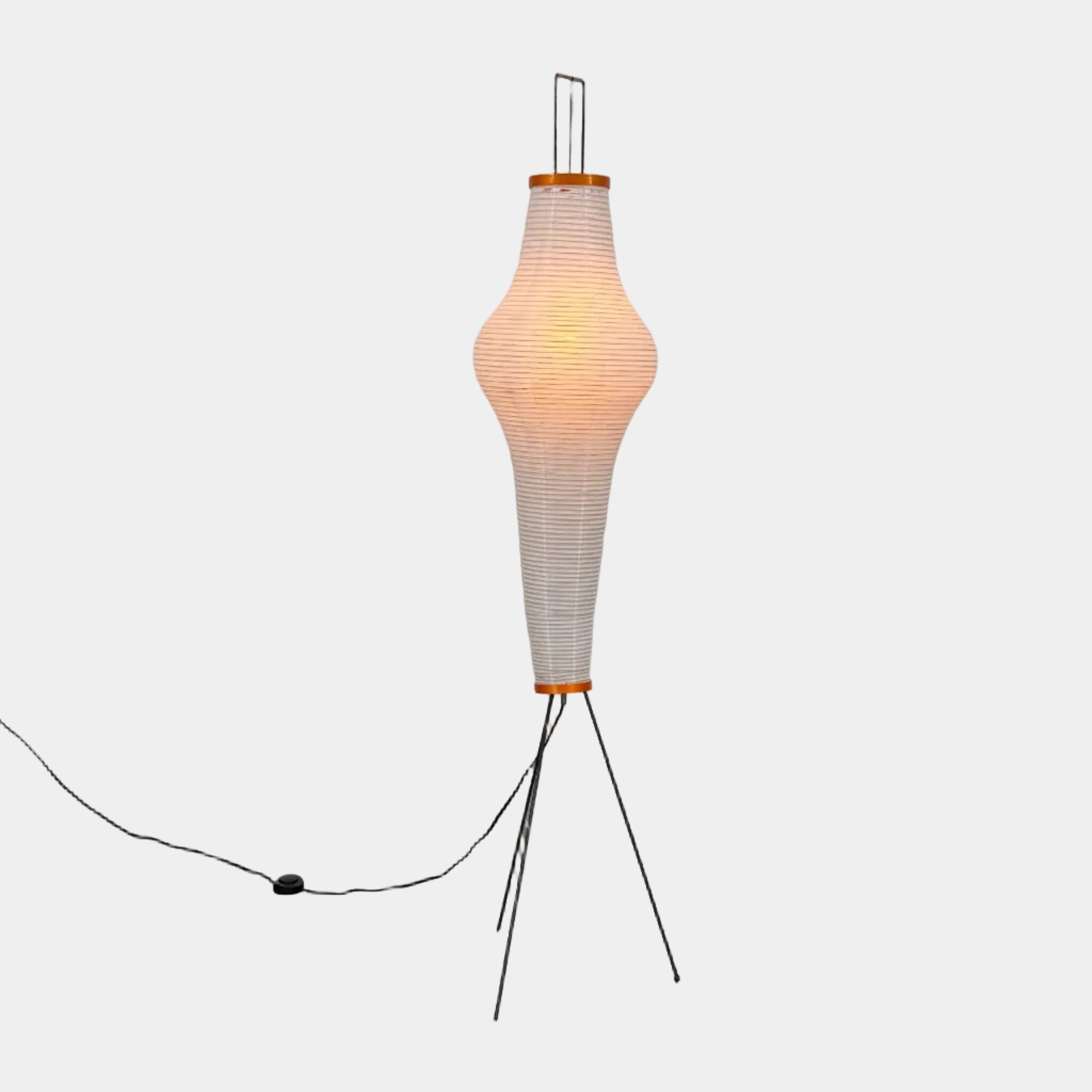 The Noguchi Araki 14A Floor Lamp by Noguchi is a tall, sculptural floor lamp inspired by Japanese craftsmanship, featuring a white ribbed shade, wooden accents, and three slender metal legs. Reminiscent of Akari Light Sculptures and the original Noguchi Araki 14A design, this plugged-in lamp is shown illuminated against a plain white background.