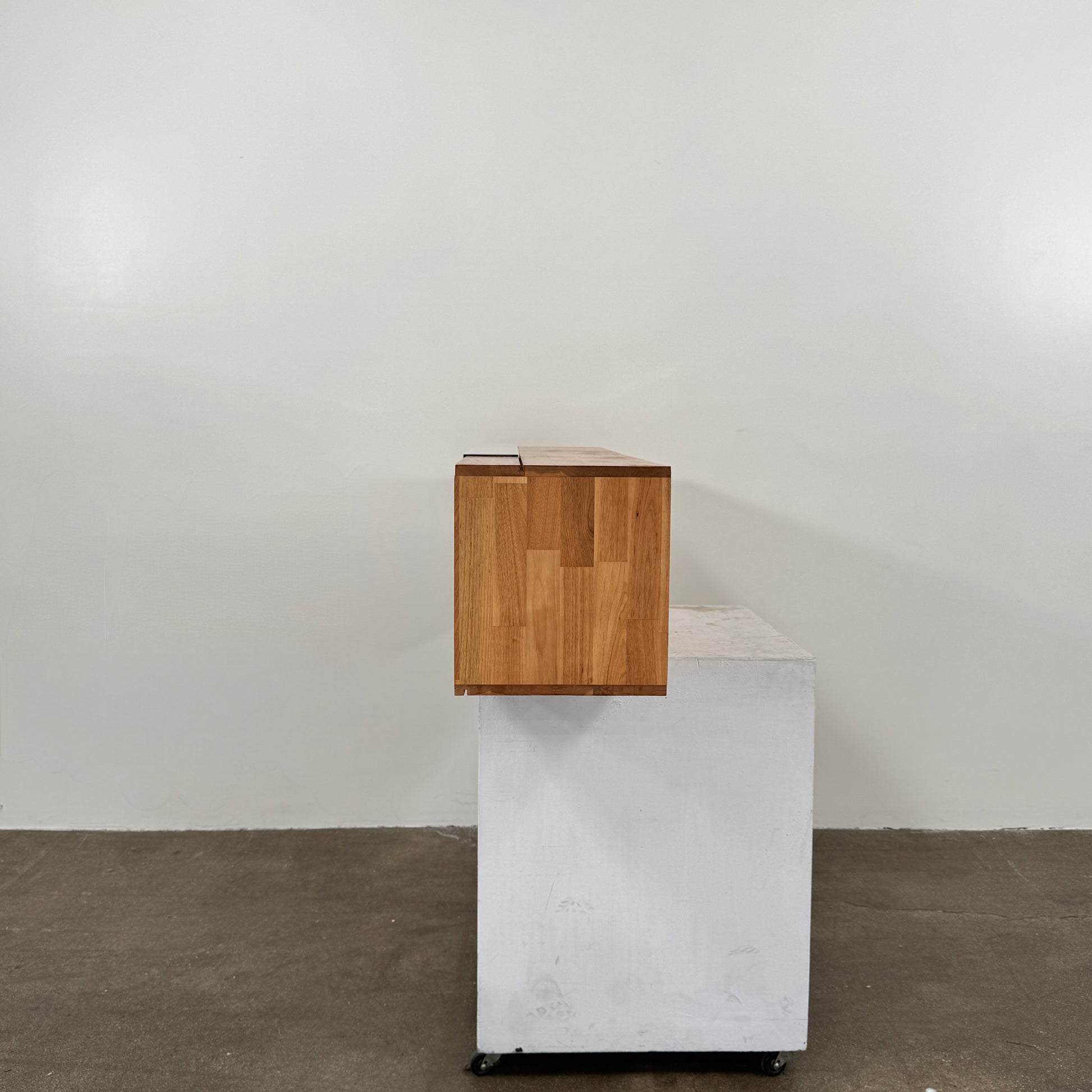The Mash Studios LAX series 3X Wall Mounted Shelf in natural ash wood and matte white features two partially open sliding doors that reveal a solid ash wood interior, and is shown here mounted on a plain wall.