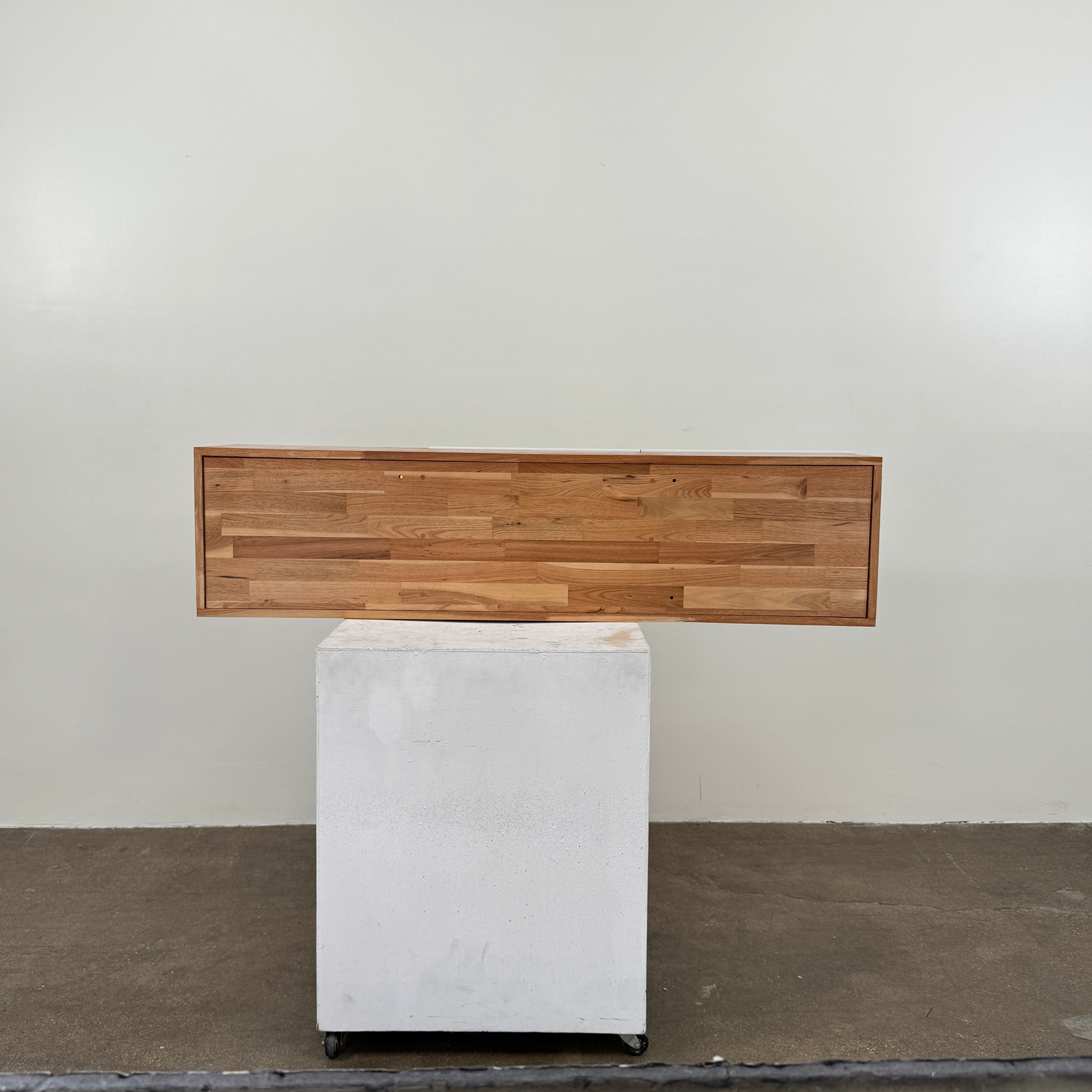 The Mash Studios LAX series 3X Wall Mounted Shelf in natural ash wood and matte white features two partially open sliding doors that reveal a solid ash wood interior, and is shown here mounted on a plain wall.