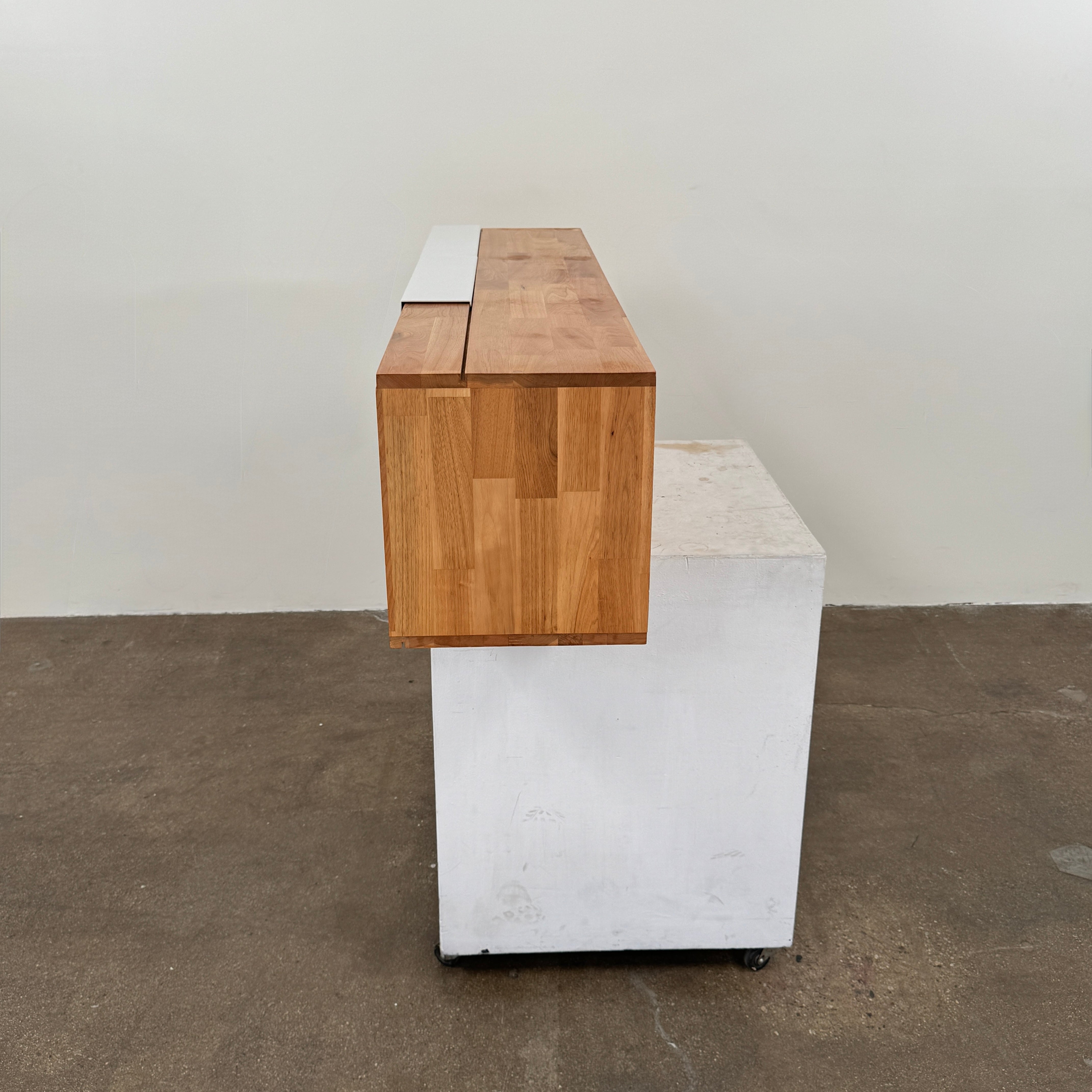 The Mash Studios LAX series 3X Wall Mounted Shelf in natural ash wood and matte white features two partially open sliding doors that reveal a solid ash wood interior, and is shown here mounted on a plain wall.
