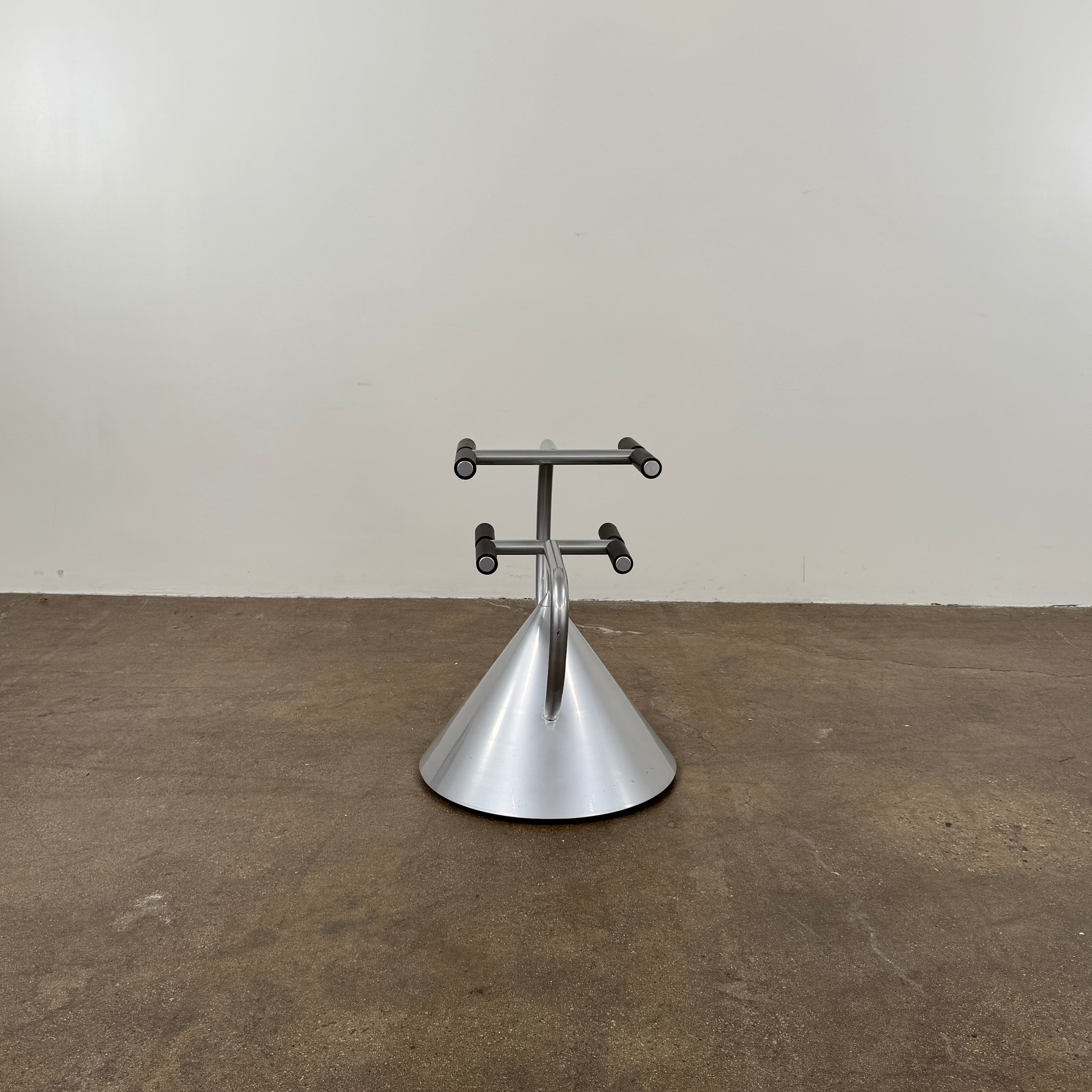 A silver metal cone base supports two curved arms with four black cylindrical grips, arranged symmetrically against a plain light background—an aesthetic reminiscent of the playful geometry seen in the Memphis movement, embodied by the Vintage Postmodern “Hotel Zeus” TV Stand for Zeus Milano by Zeus.