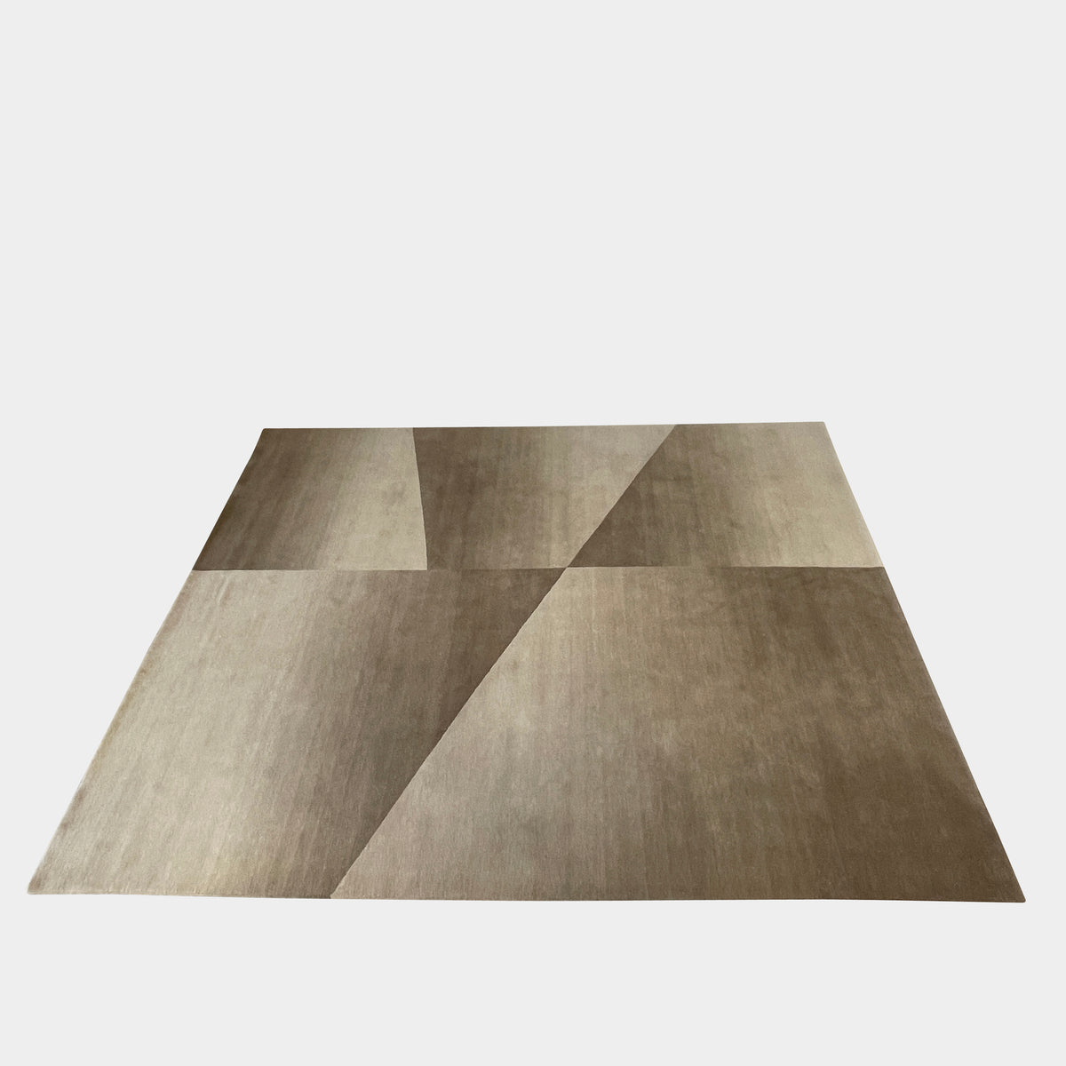 The Delinear Facet Cropped Wool Rug, offered by Delinear, is elegantly positioned on a light gray floor. It showcases modern abstract designs in beige and taupe, with diagonal lines and subtle texture.