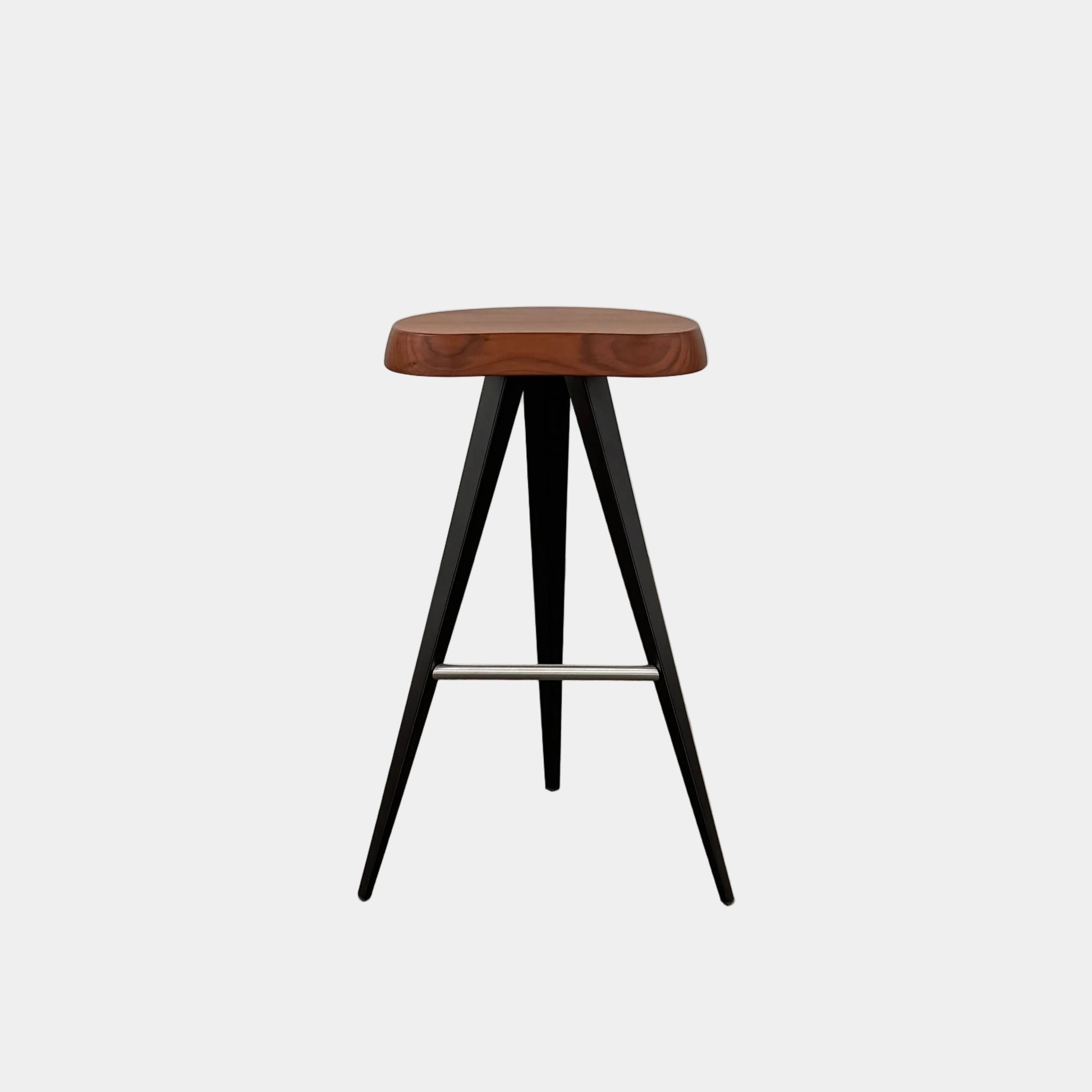 A Cassina Mexique Stool by Cassina, featuring a wooden round seat, three black angled legs, and a metal footrest, is displayed against a plain white background—highlighting its mid-century craftsmanship inspired by Charlotte Perriand.