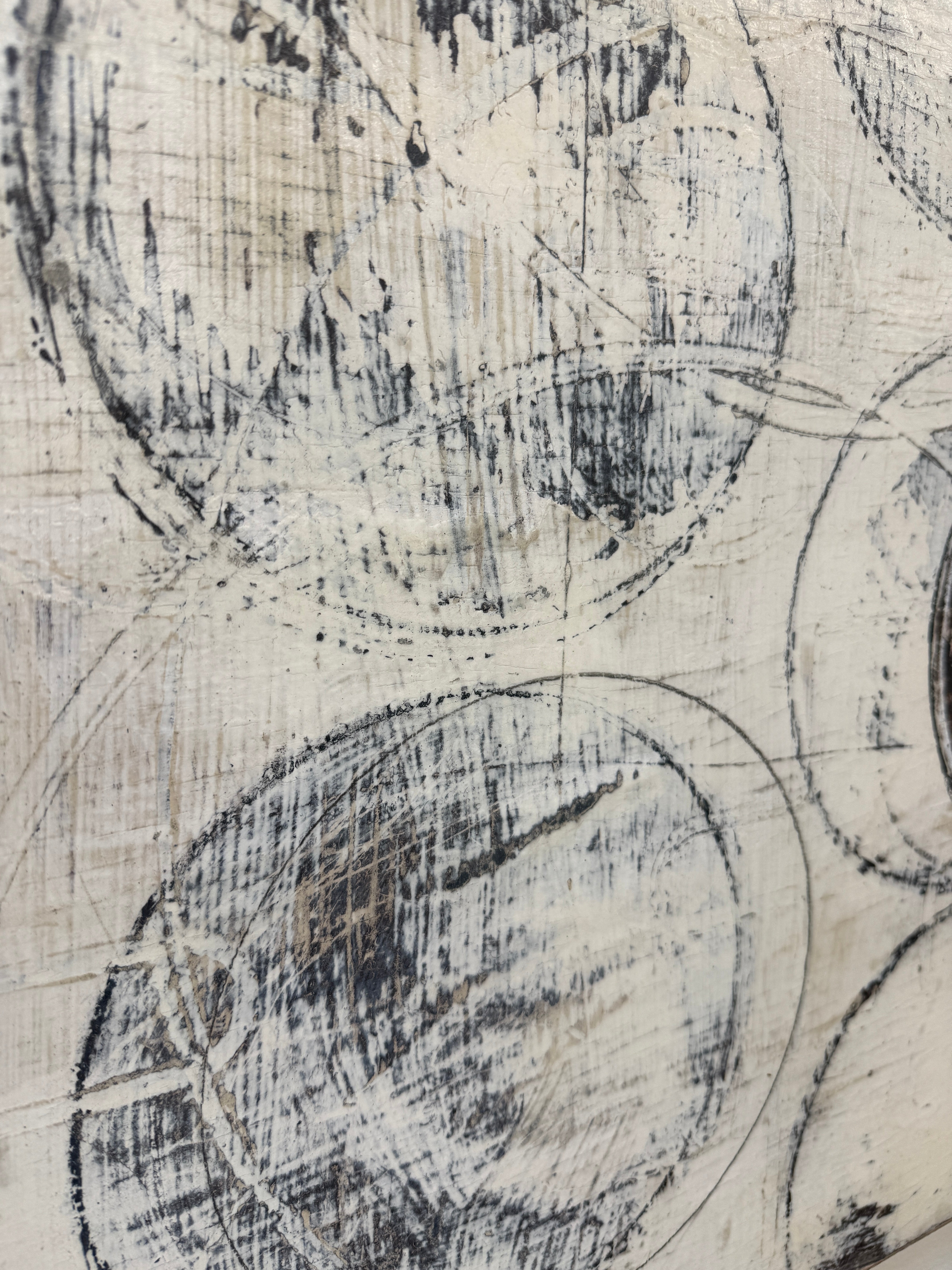 Painting: Circles by Ron Piler from Modern Resale features overlapping black and gray circles on a textured white background, displayed against a white wall on a concrete floor.