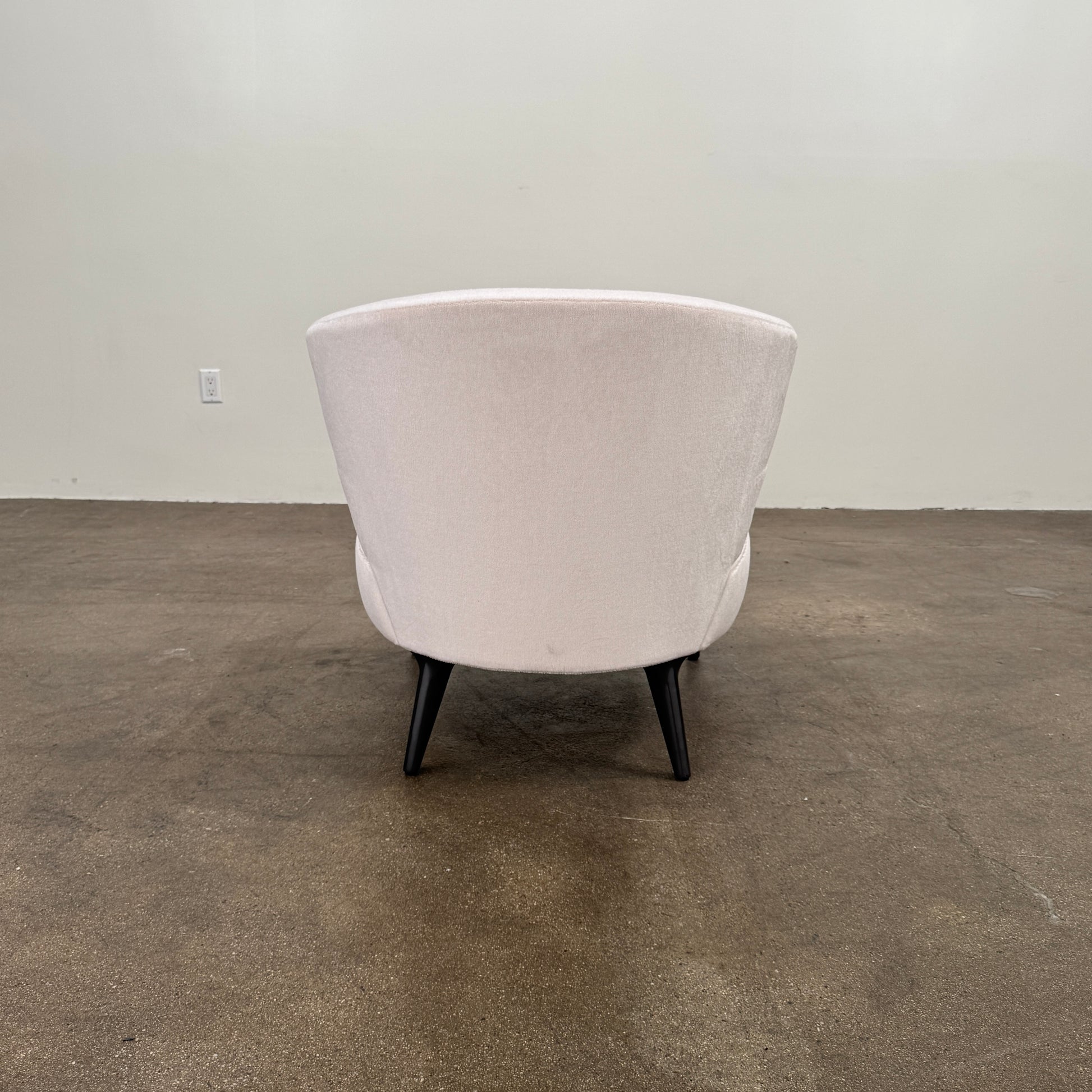 The Minotti Aston “Armchair” by Minotti features modern luxury with light pink upholstery and black wooden legs, showcased against a plain white background.