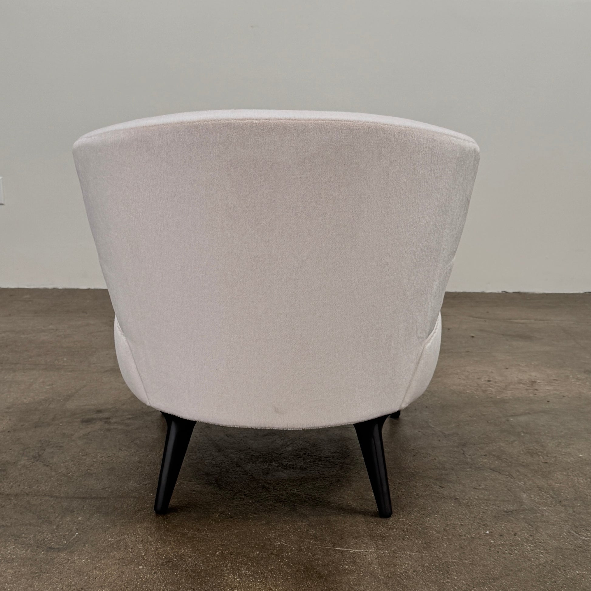 The Minotti Aston “Armchair” by Minotti features modern luxury with light pink upholstery and black wooden legs, showcased against a plain white background.