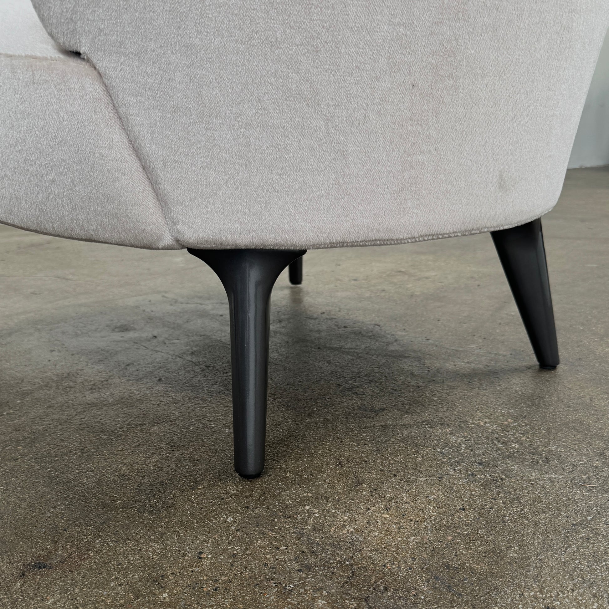 The Minotti Aston “Armchair” by Minotti features modern luxury with light pink upholstery and black wooden legs, showcased against a plain white background.