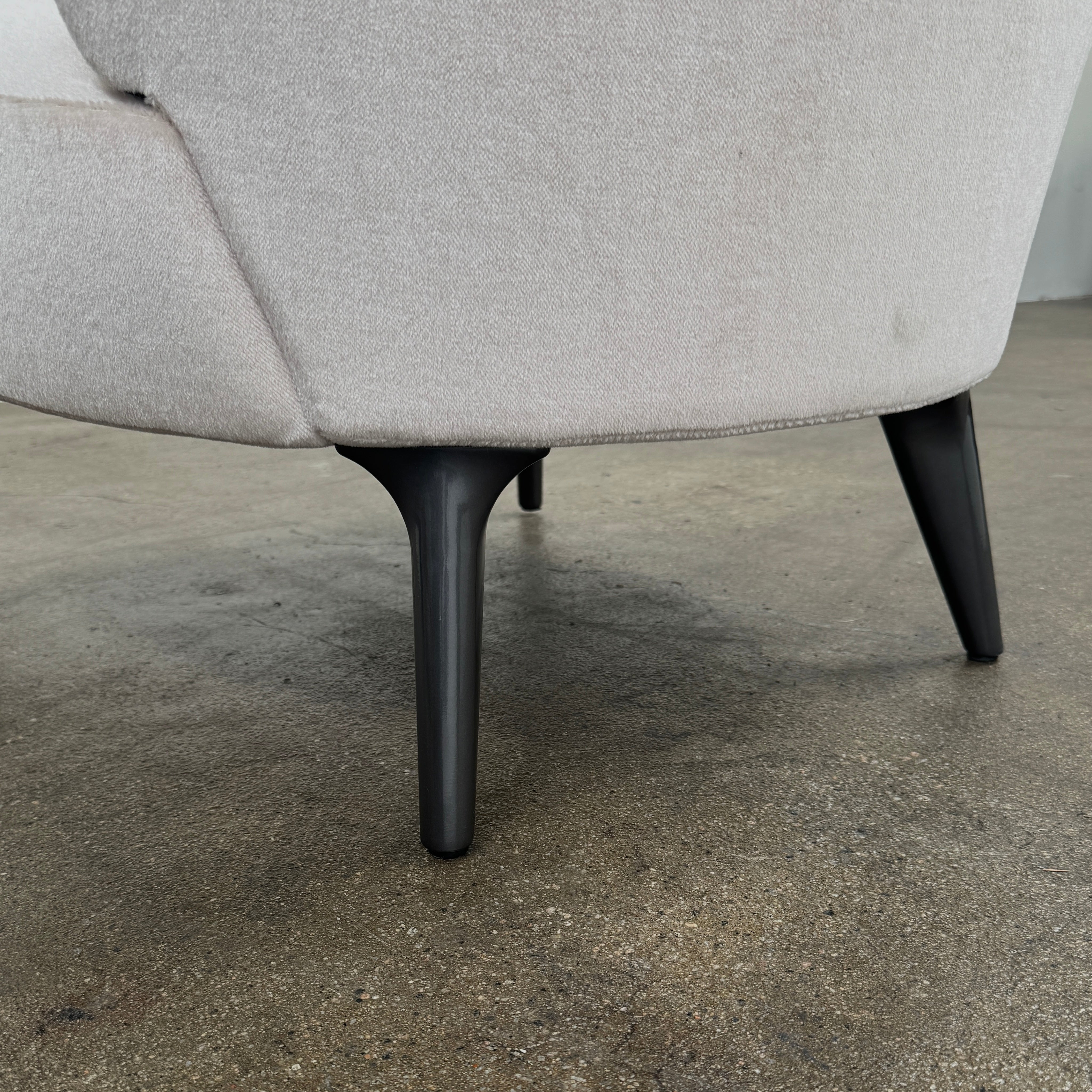 The Minotti Aston “Armchair” by Minotti features modern luxury with light pink upholstery and black wooden legs, showcased against a plain white background.