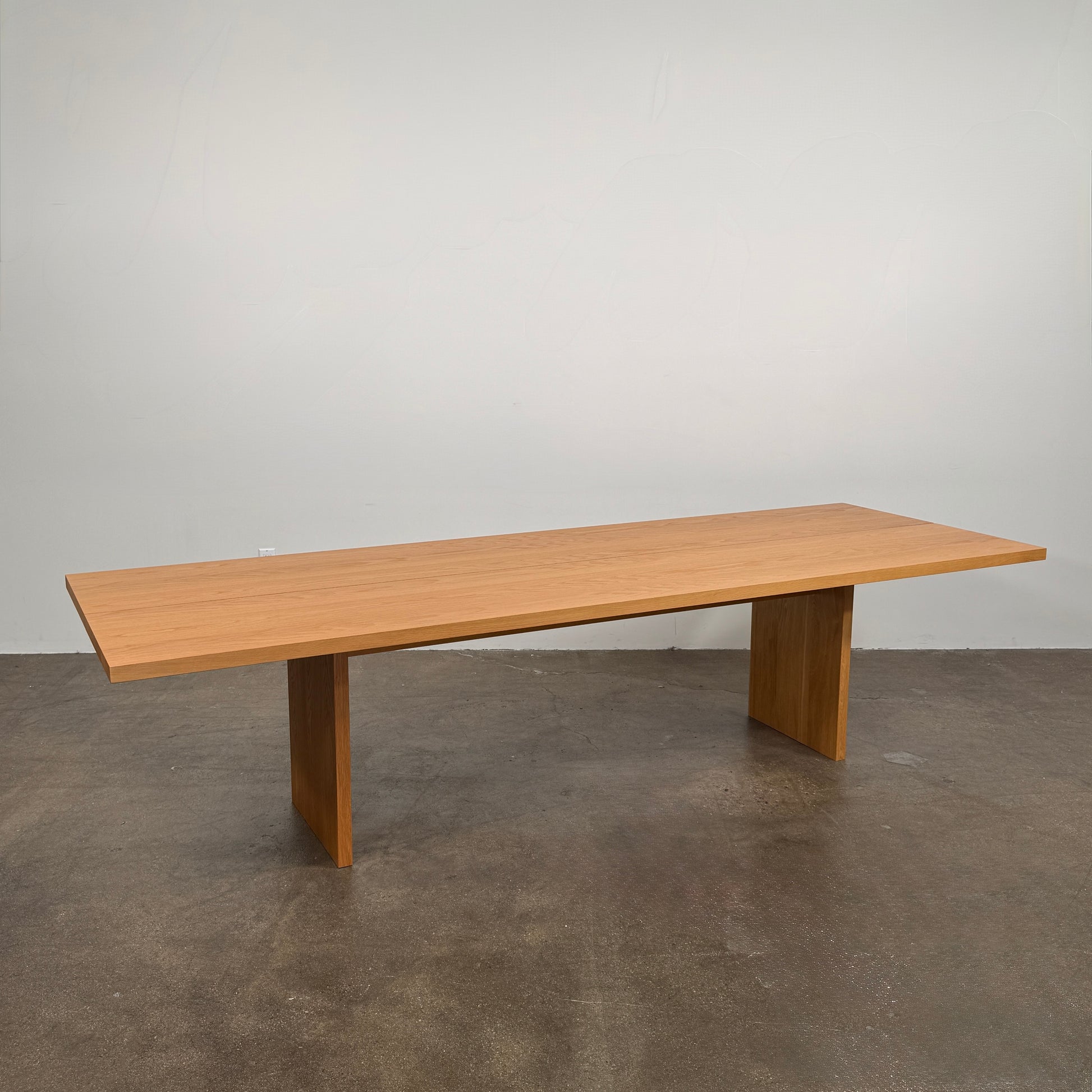 A Dk3 Gather table, crafted from solid oak with a flat rectangular top and two wide, flat legs at each end, is set against a plain white background.