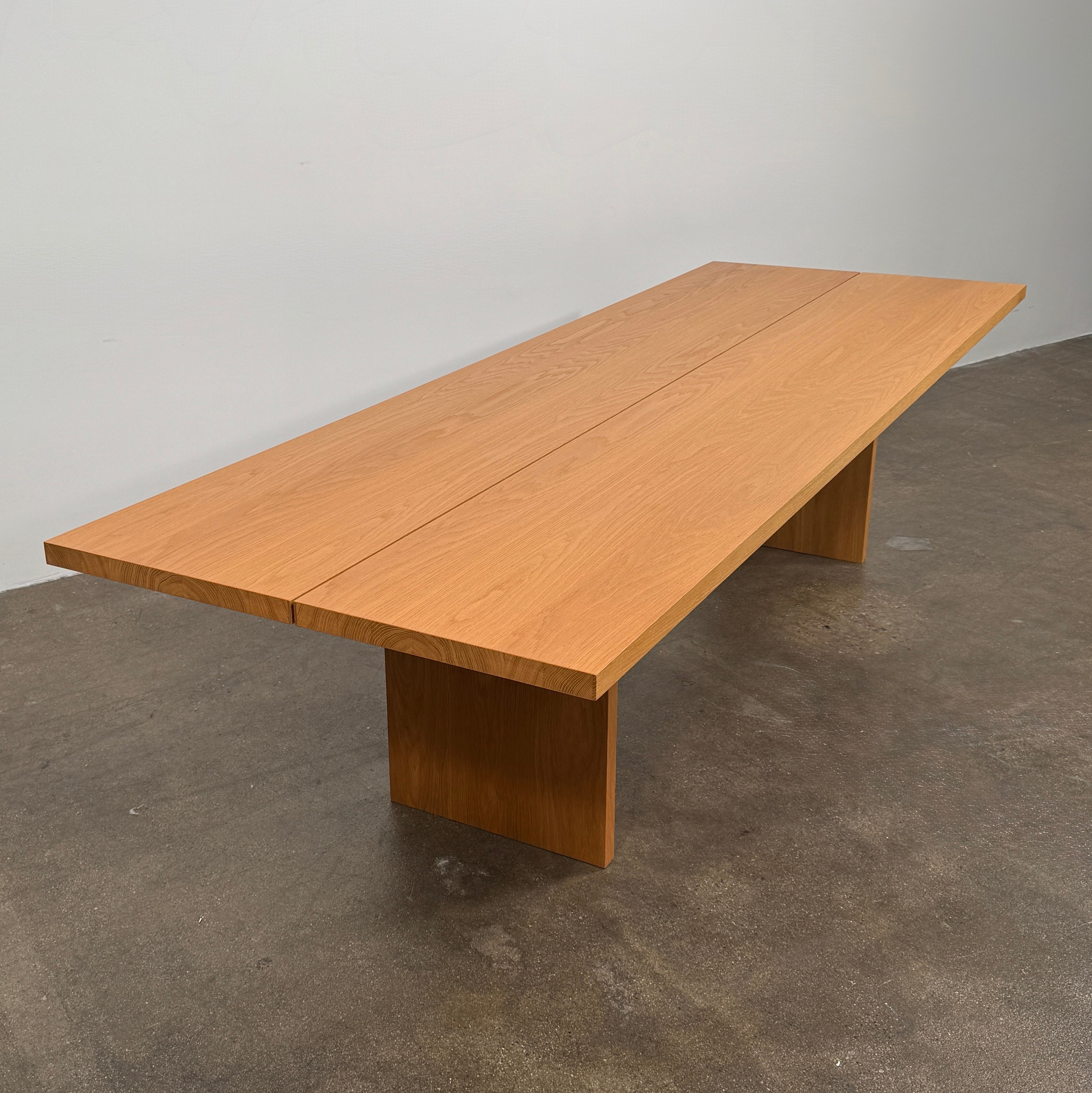 A Dk3 Gather table, crafted from solid oak with a flat rectangular top and two wide, flat legs at each end, is set against a plain white background.
