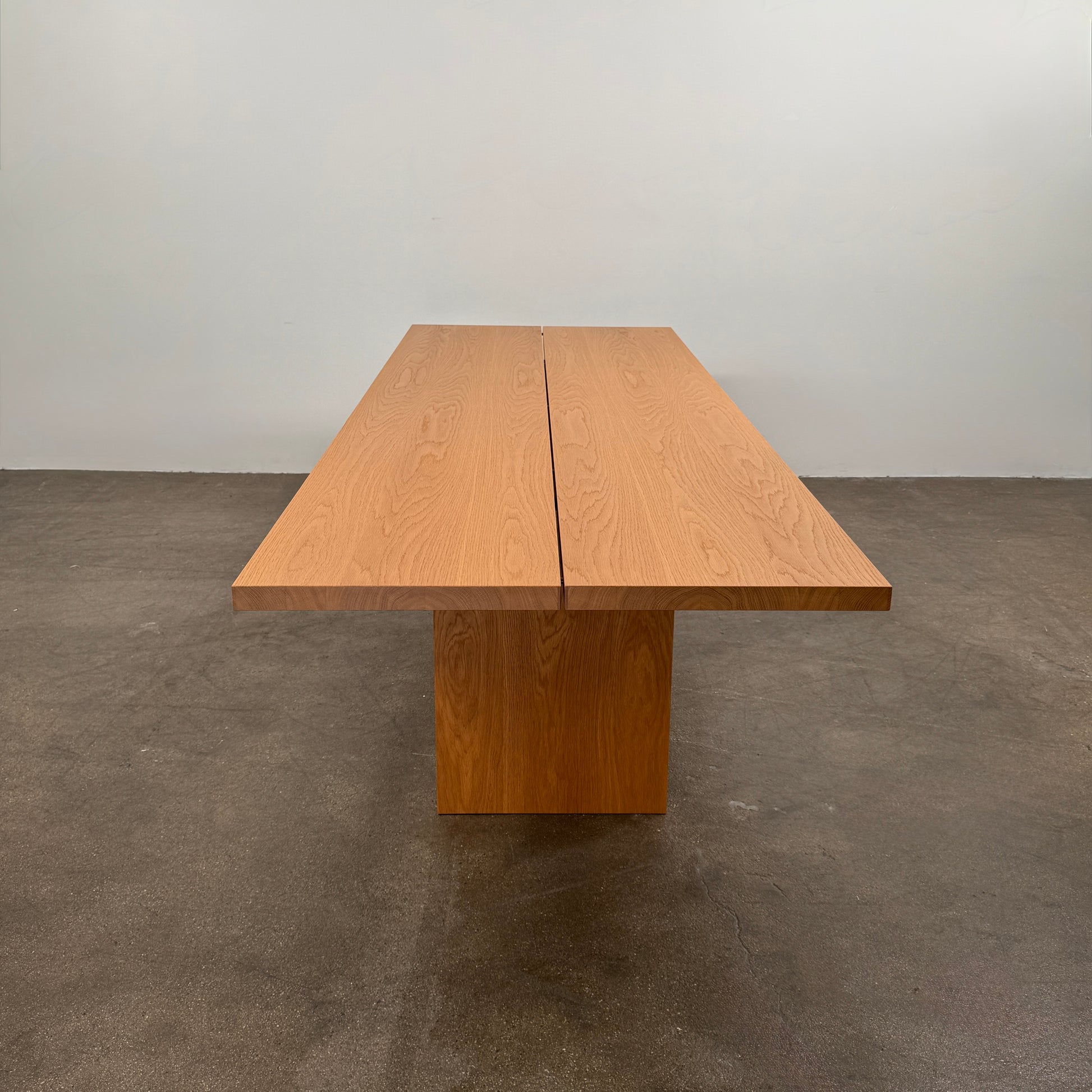 A Dk3 Gather table, crafted from solid oak with a flat rectangular top and two wide, flat legs at each end, is set against a plain white background.