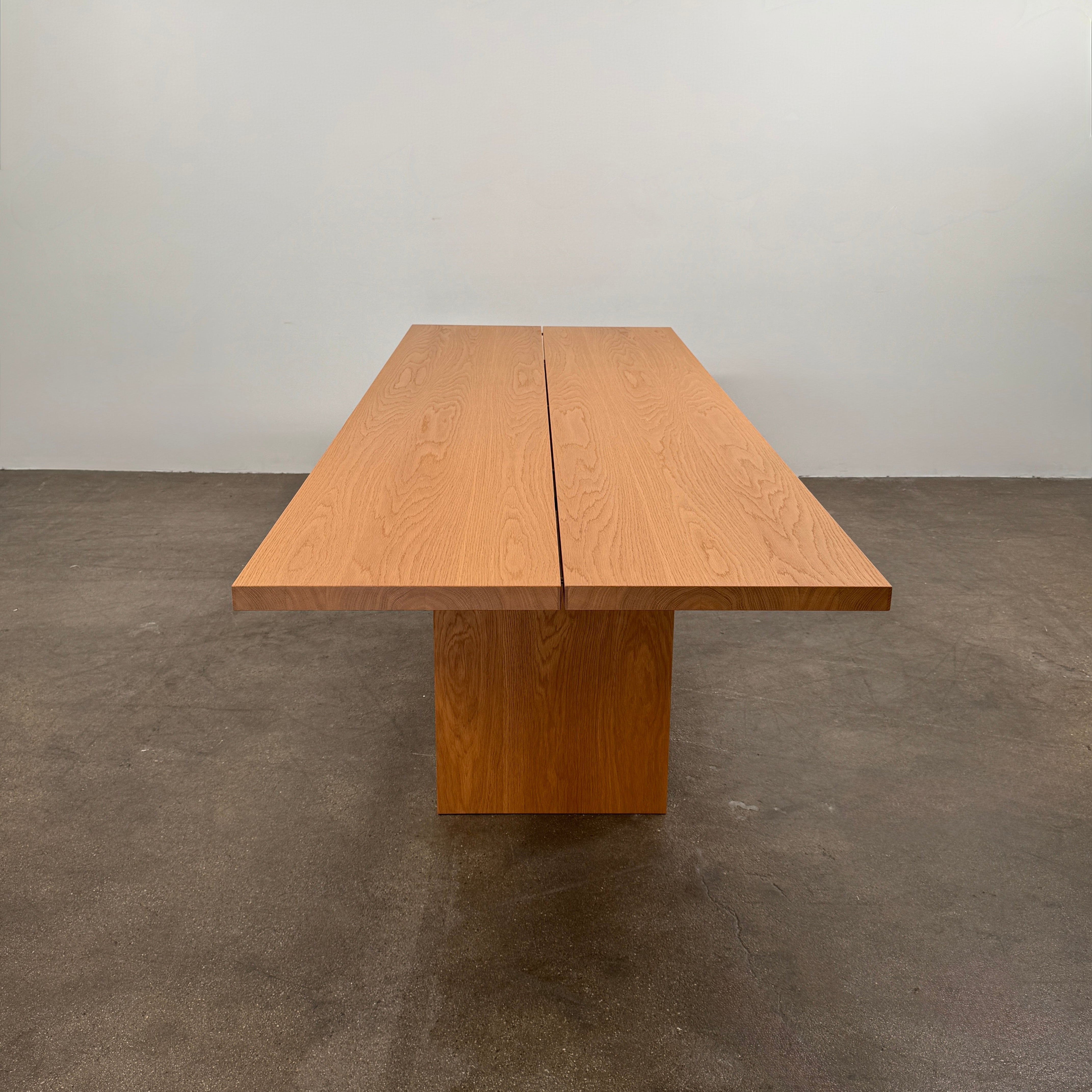 A Dk3 Gather table, crafted from solid oak with a flat rectangular top and two wide, flat legs at each end, is set against a plain white background.