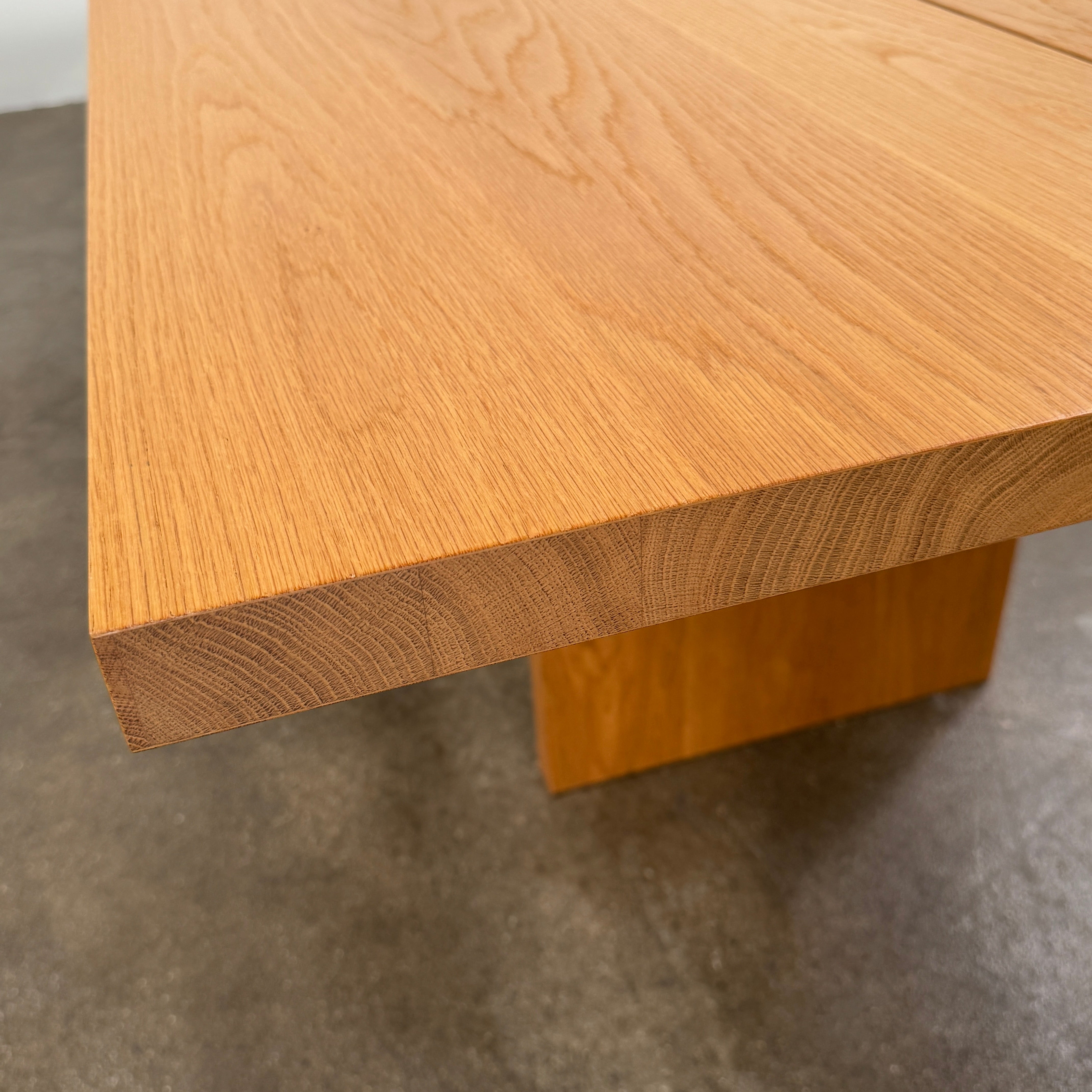 A Dk3 Gather table, crafted from solid oak with a flat rectangular top and two wide, flat legs at each end, is set against a plain white background.
