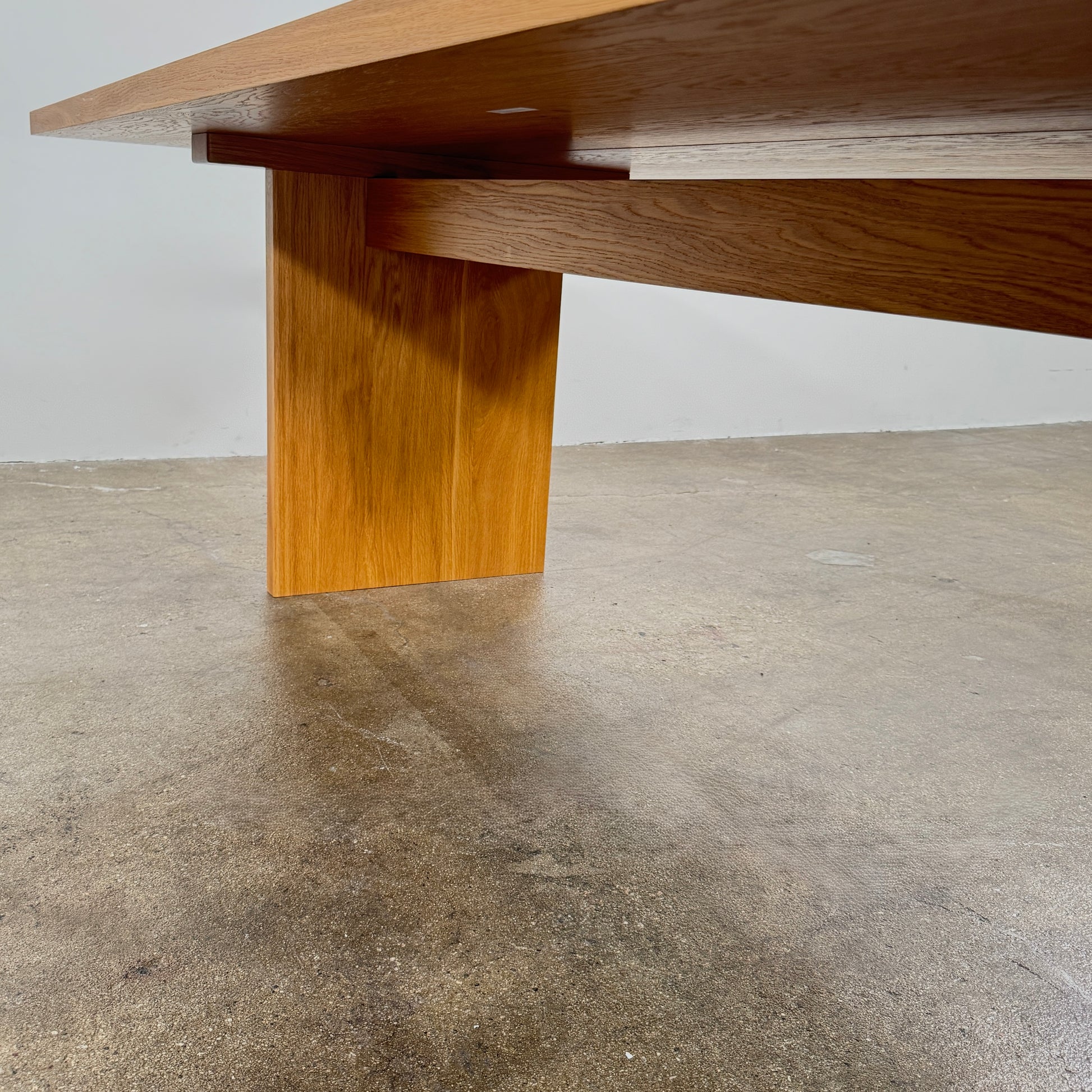 A Dk3 Gather table, crafted from solid oak with a flat rectangular top and two wide, flat legs at each end, is set against a plain white background.