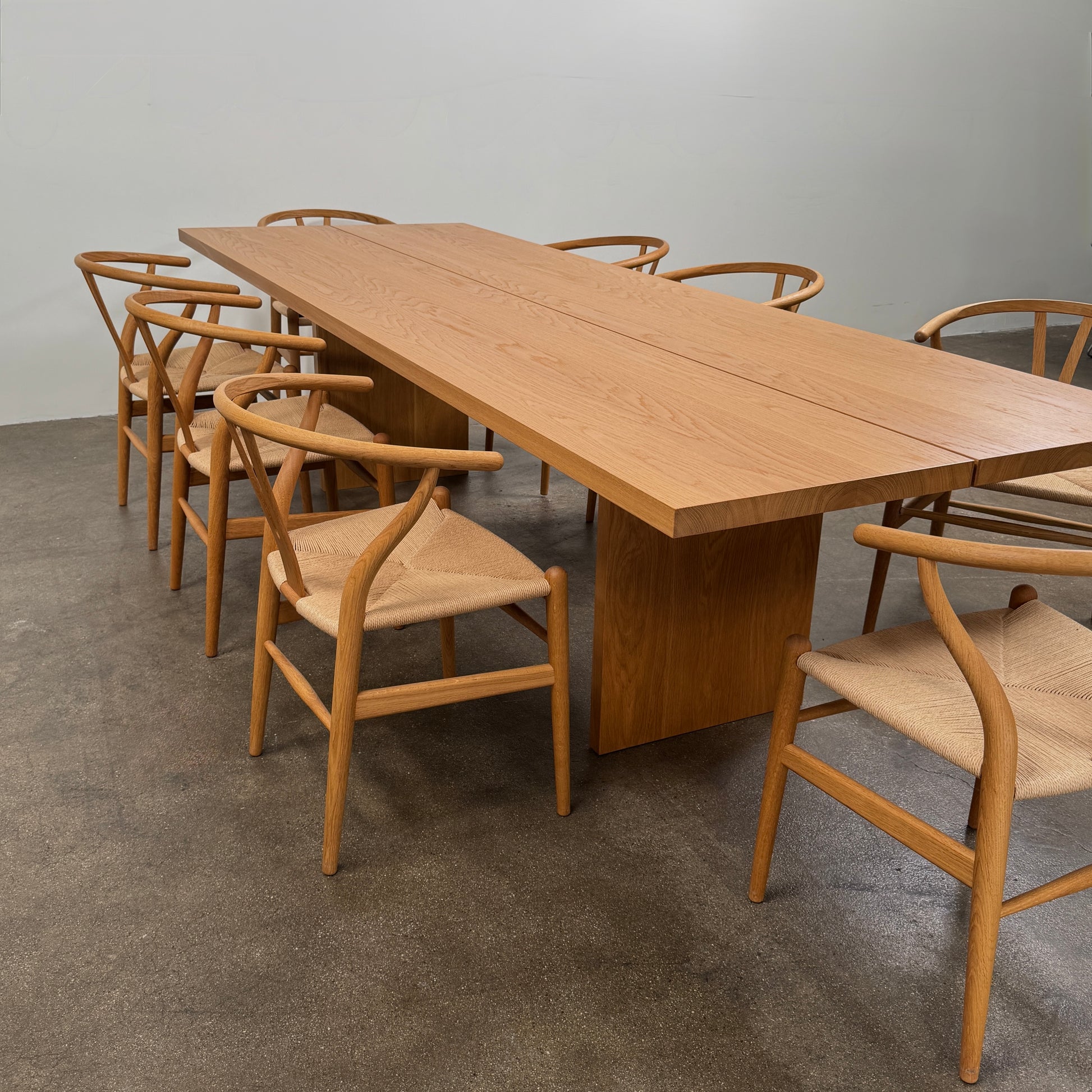 A Dk3 Gather table, crafted from solid oak with a flat rectangular top and two wide, flat legs at each end, is set against a plain white background.