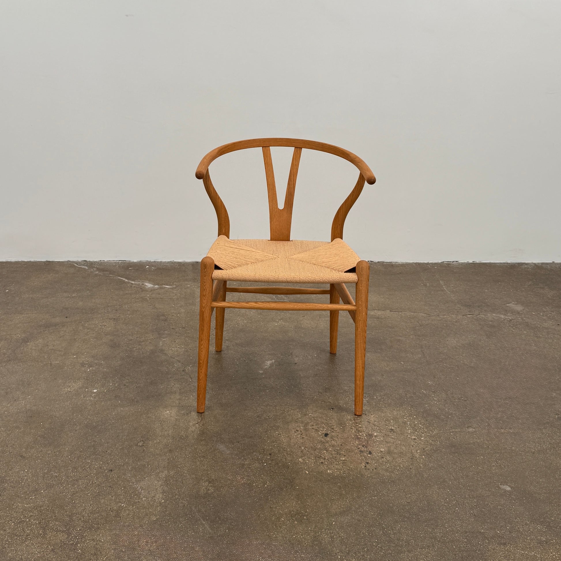 A set of two Carl Hansen & Søn Wishbone Dining Chairs by Carl Hansen & Son, featuring curved backrests and woven seats, are displayed side by side against a plain white background to highlight the renowned Danish craftsmanship inspired by Hans Wegner’s iconic design.