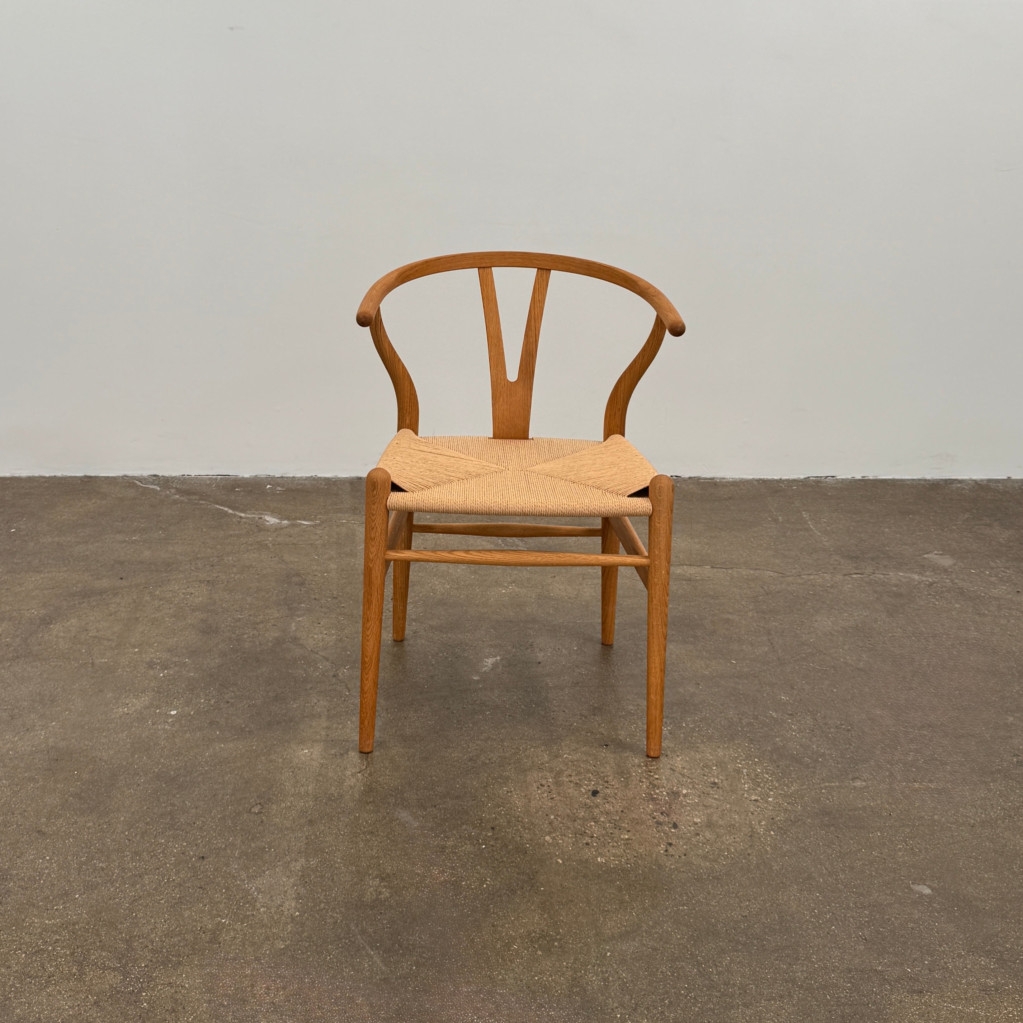 A set of two Carl Hansen & Søn Wishbone Dining Chairs by Carl Hansen & Son, featuring curved backrests and woven seats, are displayed side by side against a plain white background to highlight the renowned Danish craftsmanship inspired by Hans Wegner’s iconic design.